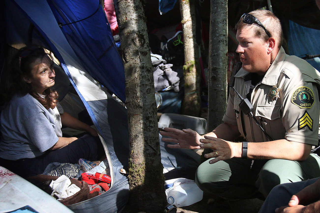 Genna Martin / The HeraldSnohomish County Sheriff's Deputy Sgt. Ian Huri speaks with Rochelle Hammond at a homeless encampment in Everett, August 26.  Sgt. Huri and social worker  Jesse Callihan have been working with Hammond and other residents to get them connected with detox programs, housing and other social services. Photo taken 08262015