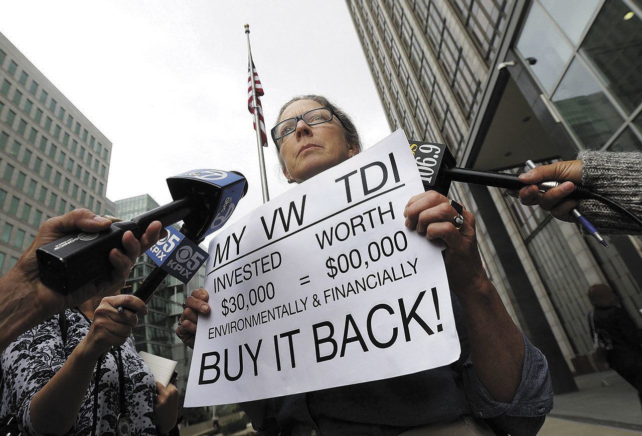 Joyce Ertel Hulbert, owner of a 2015 Volkswagen Golf TDI, holds a sign while interviewed outside of the Phillip Burton Federal Building in San Francisco on April 21. (Jeff Chiu / Associated Press)