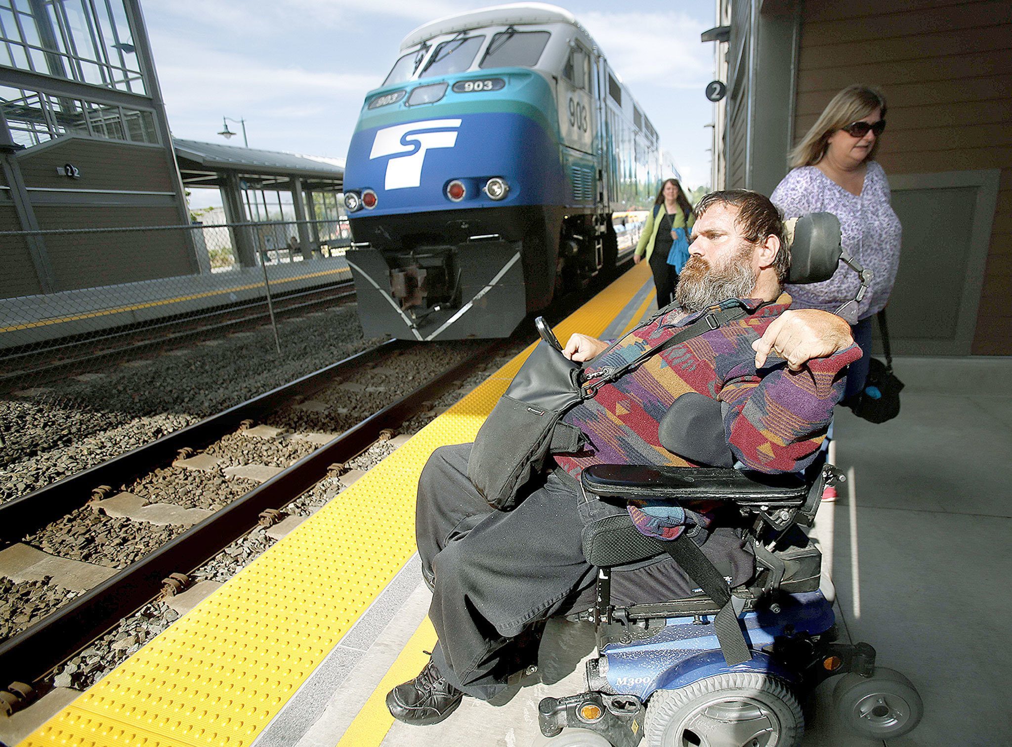 At the Mukilteo Station, Kent McDaniel watches as the Sounder pulls into the northbound passenger loading dock and passengers begin to depart onto the platform on the east side of the Mukilteo Station, which is on the opposite side of the tracks from the main one and parking lot. Previously McDaniel missed a lot of trains due to not knowing which track they were stopping at prior to their arrival, and him being unable to cross over in time in his wheelchair. (Dan Bates / The Herald)