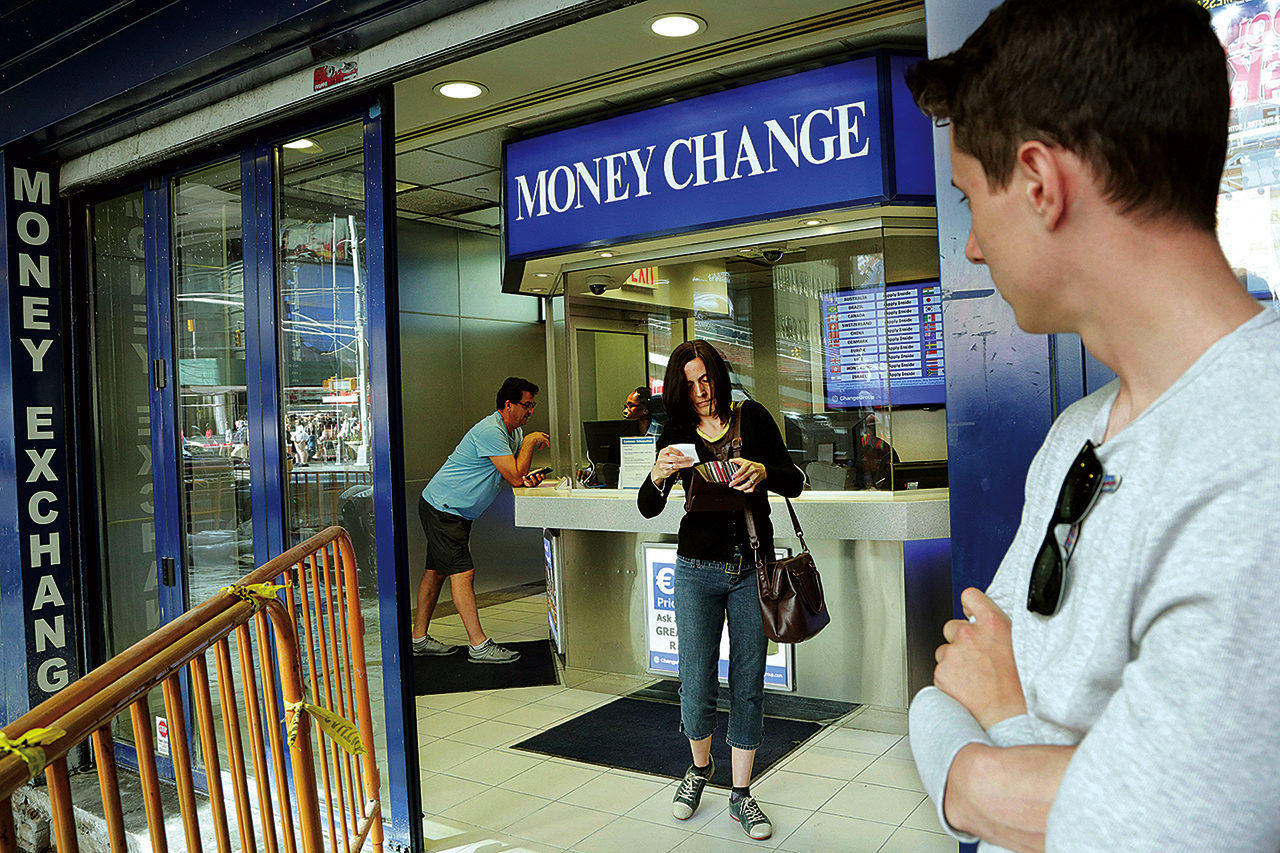 Claire Hunt, center, of Reading, England, changes pounds for dollars on Friday at a money exchange in New York. (AP Photo/Mark Lennihan)