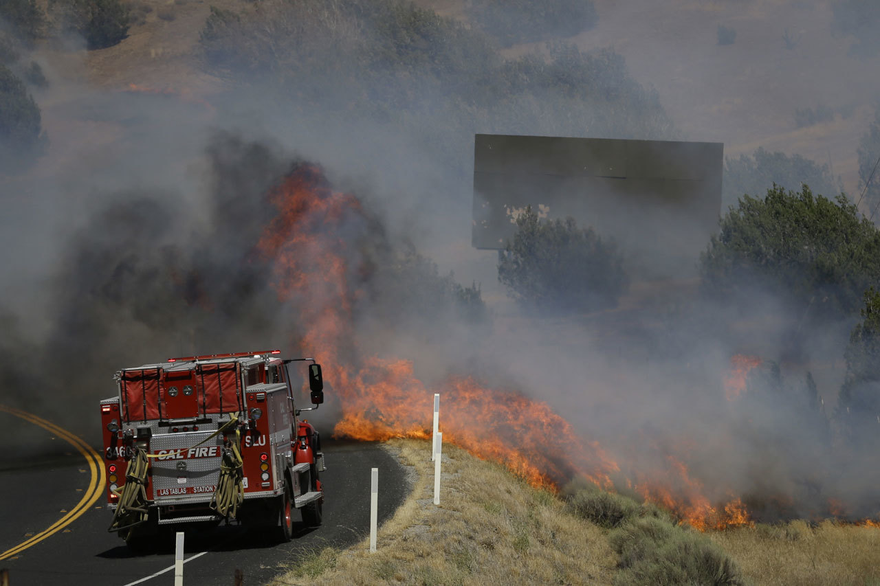 A flame from a wildfire approaches a fire truck as it moves along Highway 178 near Lake Isabella, California, on Friday. The wildfire that roared across dry brush and trees in the mountains of central California gave residents little time to flee as flames burned homes to the ground, propane tanks exploded and smoke obscured the path to safety. (Jae C. Hong / Associated Press)