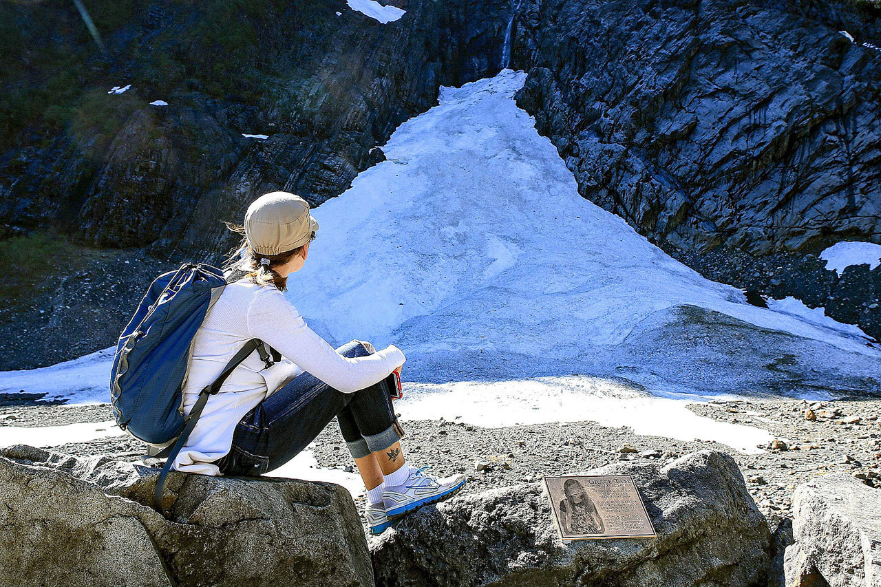Connie Peterson looks at the snow pack at the Big Four Ice Caves east of Granite Falls on May 1. The popular hike and attraction was closed for months after a deadly collapse in July 2015. At right is a memorial plaque to Grace Tam, 11, who died July 31, 2010, at the caves. Tam was 20 feet from the caves. (Kevin Clark / Herald file)