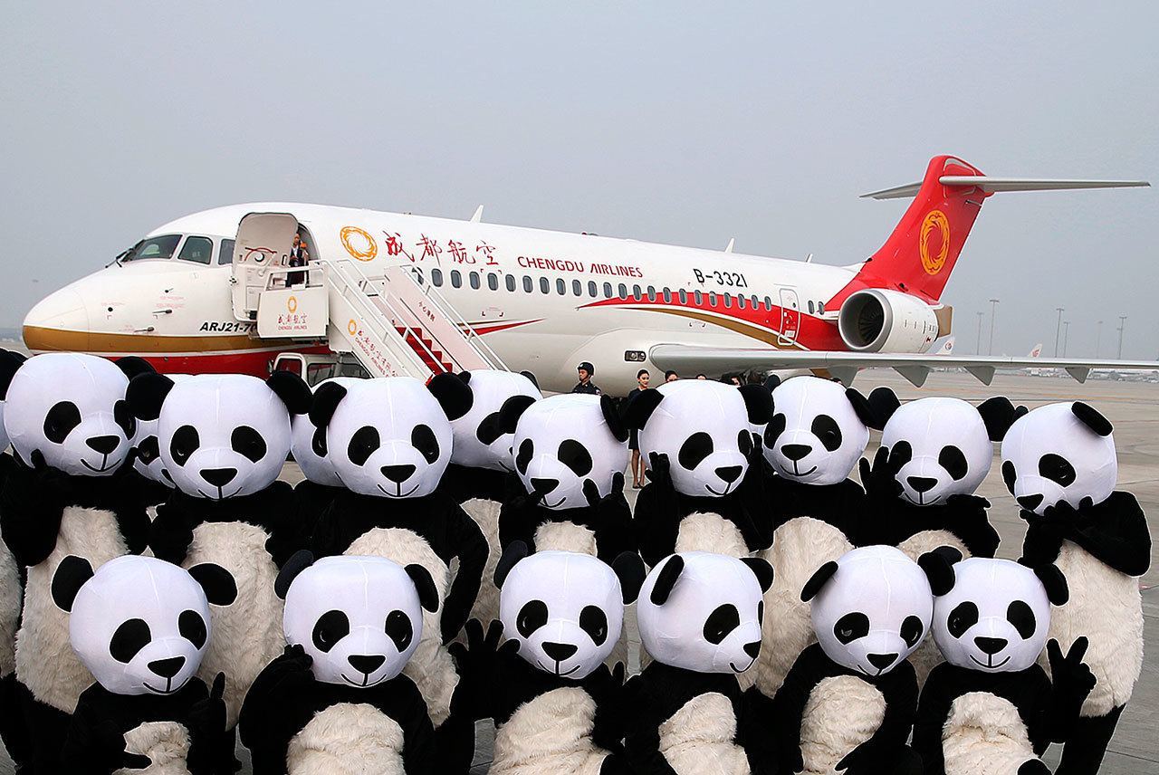 People in panda costumes pose in front of a Chengdu Airlines ARJ21-700 plane before its first commercial flight at Chengdu Shuangliu International Airport in Chengdu in southwestern China’s Sichuan Province on Tuesday. The ARJ21-700, made by the Commercial Aircraft Corporation of China Ltd. (COMAC), is China’s first homegrown regional airliner and can seat 78 to 90 passengers, depending on its configuration. (Ding Ting / Xinhua)