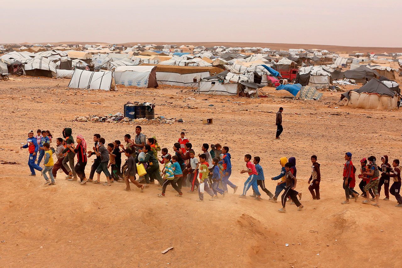 In this May 4 photo, Syrian refugee boys await approval to enter Jordan at the Hadalat reception area on the Syrian-Jordanian border, about 200 miles northeast of the capital of Amman. The U.N. refugee agency said that persecution and conflict in places like Syria and Afghanistan raised the total number of refugees and internally displaced people worldwide to a record 65.3 million at the end of last year. (Raad Adayleh, Associated Press, file)