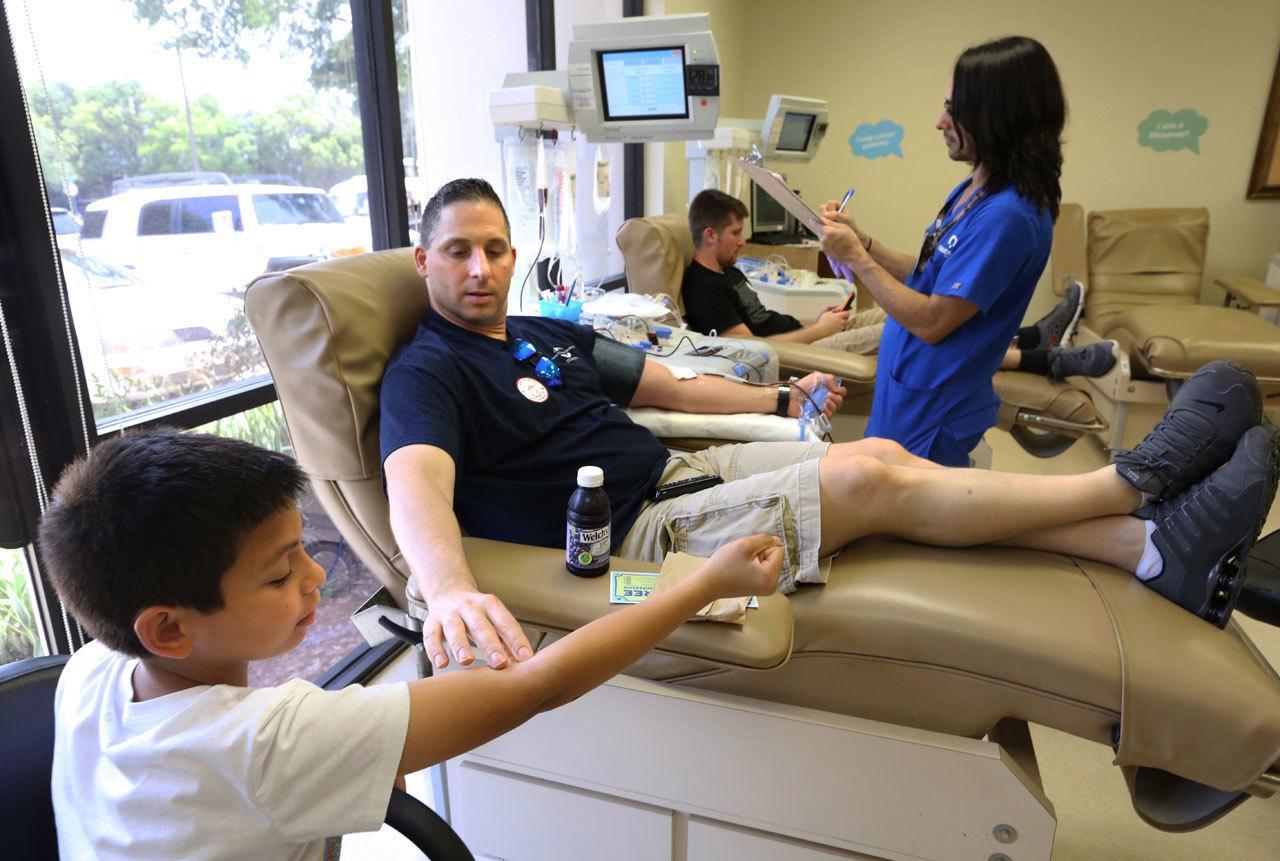 Damon Friedburg of Orlando shows his son Kellen, 12, how he is giving blood at the OneBlood center in Orlando on June 13. Area blood centers were crowded with donors giving blood in the wake of the Pulse nightclub massacre in Orlando, Florida. (Joe Burbank / Orlando Sentinel)