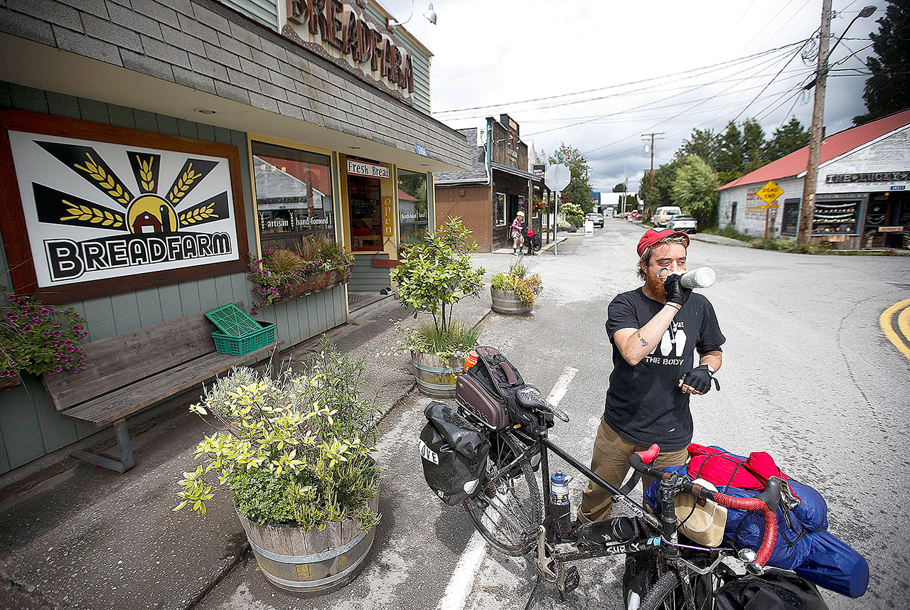 Steve Roche of Bellingham takes a sip of water after stopping for a bite to eat at the Breadfarm in Edison on Thursday. Roche is traveling to San Francisco by bicycle and made Breadfarm, a bakery founded by Scott Mangold and Renee Bourgault in 2003, the first stop of his trip. (Ian Terry / The Herald)