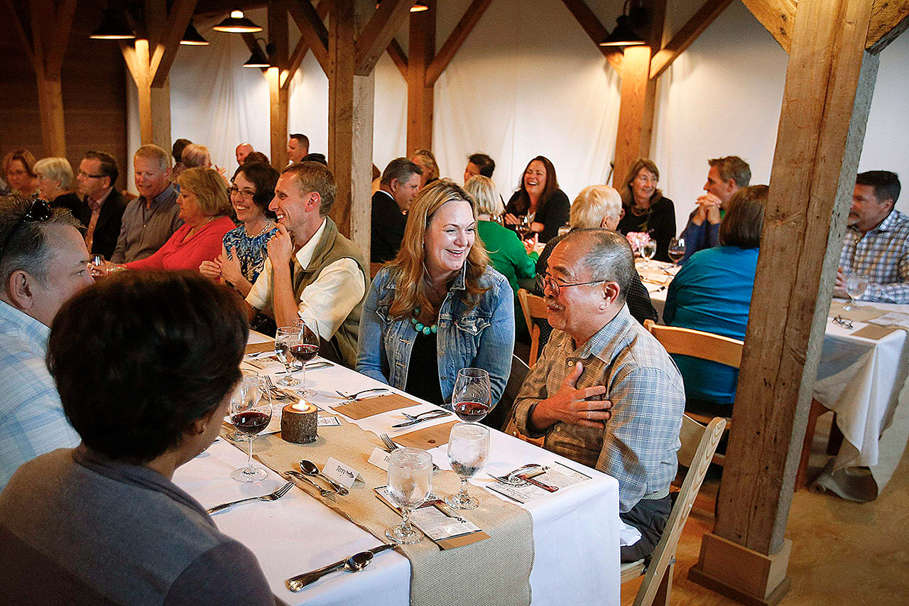 Amy Gorman (center), of Camano Island, laughs as Tino Senon (right) tells a story during the June 11 dinner at Kristoferson Farm on Camano Island. The five-course dinners feature food paired with wines from a visiting vineyard. (Ian Terry / The Herald)