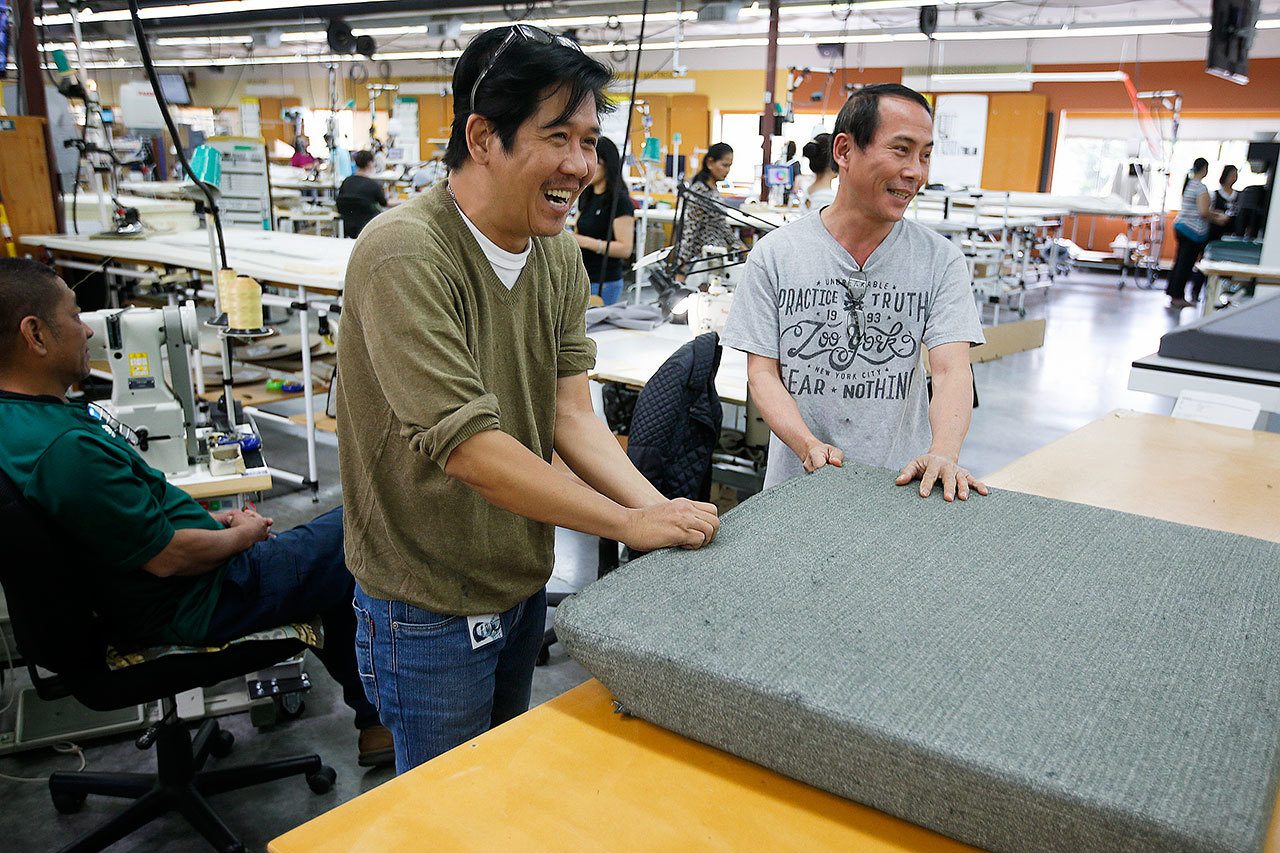 Kaas Tailored employees Duy Pham (center) and Bao Ngo (right) laugh together as they work on an airplane cushion at the company’s Mukilteo headquarters. Kaas Tailored has adopted the Japanese business practice of kaizen, which calls for each employee to make steady and consistent changes to improve overall workflow and satisfaction. (Ian Terry / The Herald)