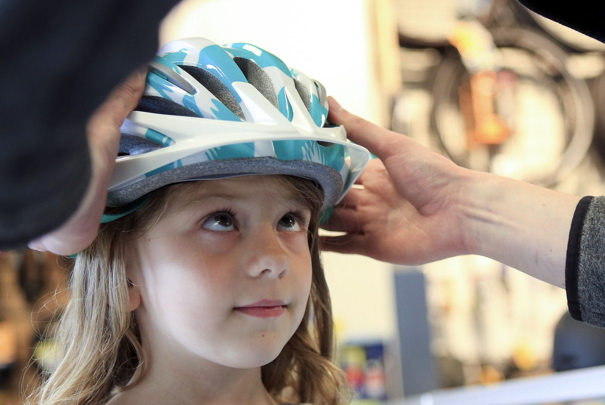 Bayside Bikes owner Eric Smith does a “shake test” to see if a helmet is properly sized for the reporter’s daughter, Geneva, 5. (Kevin Clark / The Herald)