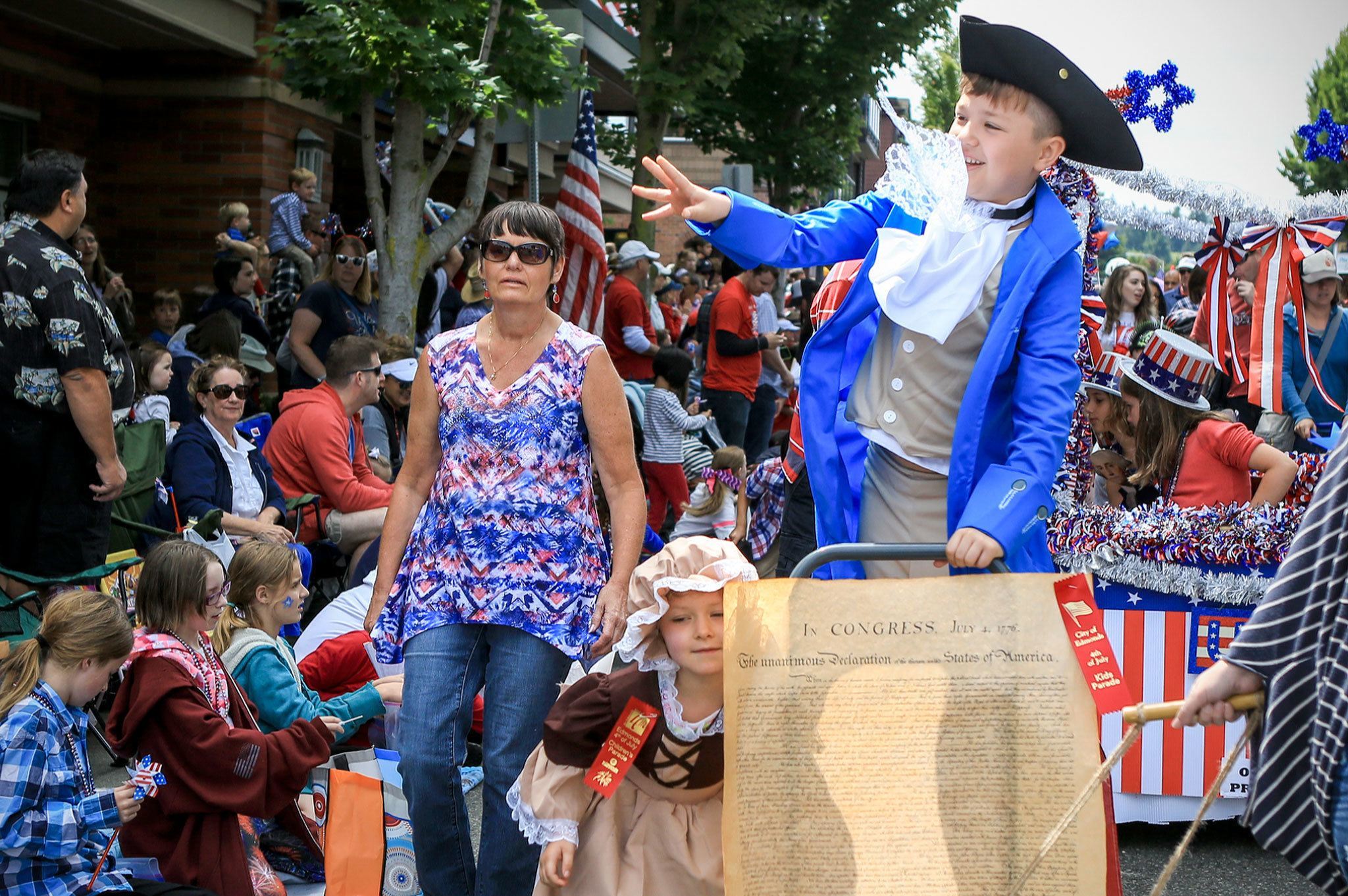 Luke Ferrell (right) throws a candy with Cecilia Jordan, left, gathering more sweets during the annual Children’s Parade Monday morning in Edmonds. (Kevin Clark / The Daily Herald)