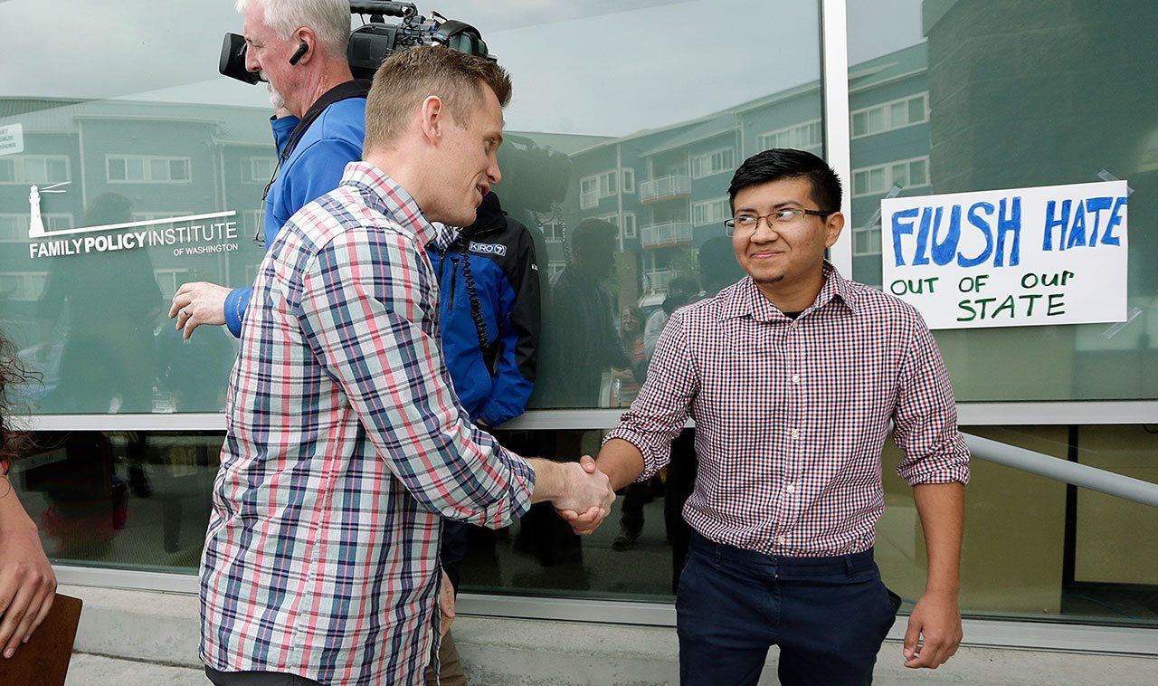 Joseph Backholm (left), executive director of the Family Policy Institute of Washington, shakes hands with Yes Segura, of the LGBTQ Allyship, after the two spoke following Segura’s group’s attempt to confront supporters of proposed Initiative 1515, in Lynnwood on Thursday. (Elaine Thompson / Associated Press)