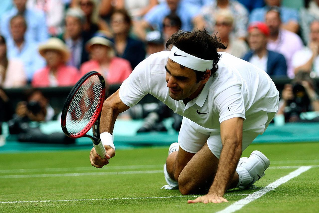Roger Federer falls over during his Wimbledon men’s semifinal singles match against Milos Raonic on Friday in London. (Clive Brunskill/Pool Photo via AP)
