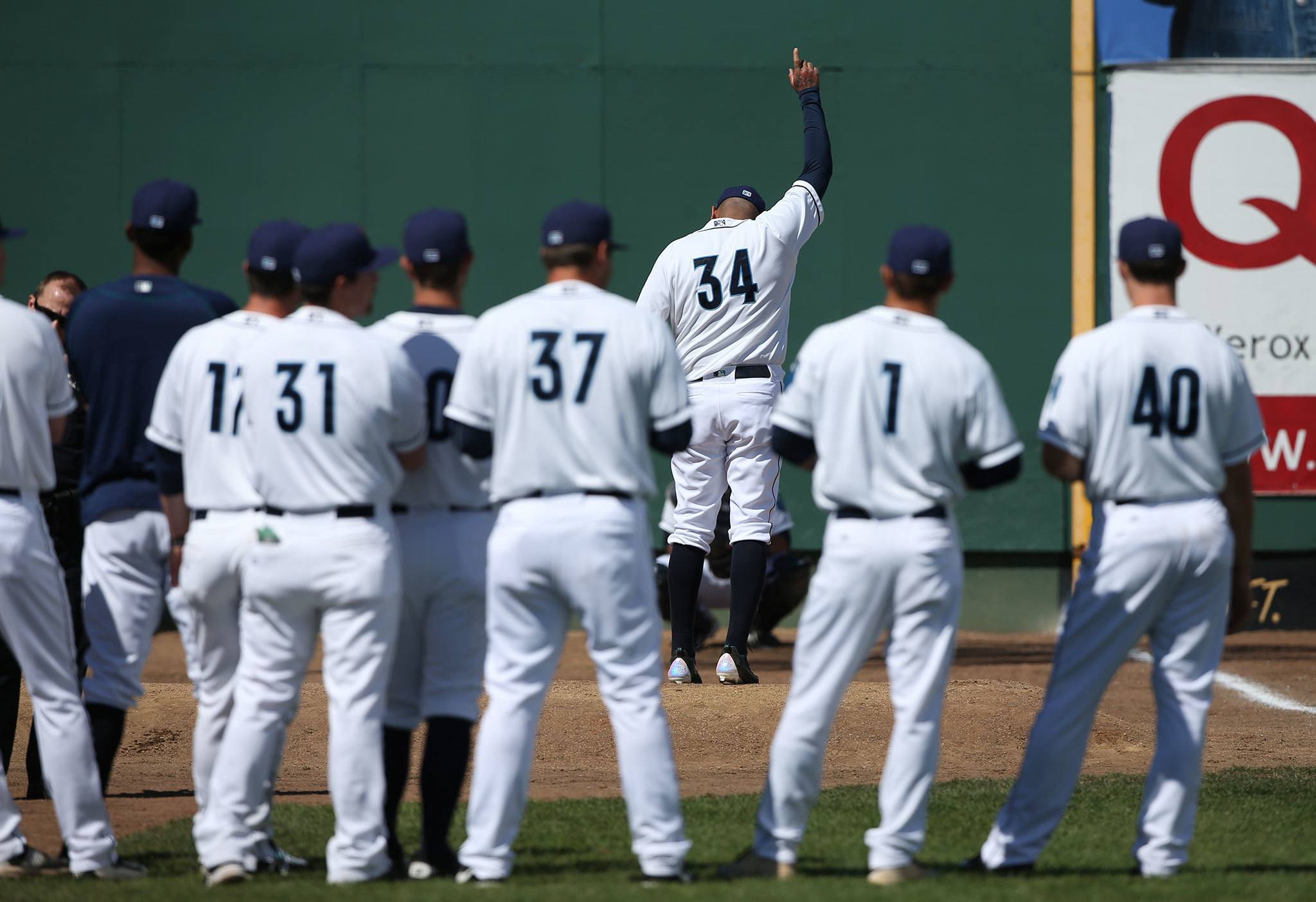 While Everett players watch his warm-up, Seattle Mariners’ ace Felix Hernandez holds up a finger at his introduction before the AquaSox played a game against the Spokane Indians at Everett Memorial Stadium on Sunday, July 10, 2016 in Everett, Washington. (Andy Bronson / The Herald )
