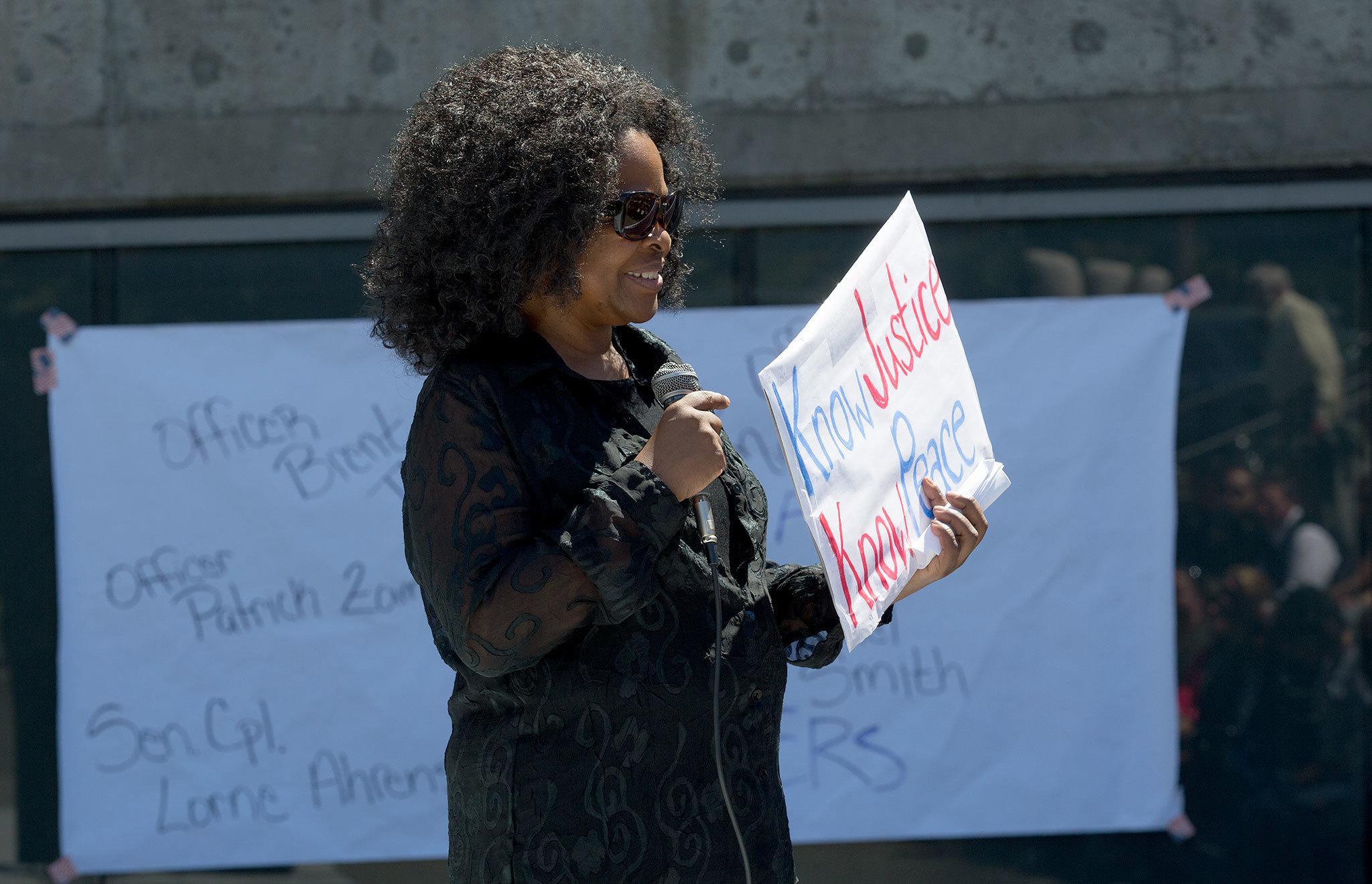 With the names of those killed in Dallas behind her, Janice Green, president of the NAACP of Snohomish County, holds up a sign at a “Stop the Hate and Do Something” vigil, with the purpose of mourning the recently slain African American Men and Police Officers, at Snohomish County Courthouse on Sunday, July. 10, 2016 in Everett, Wa. ( Andy Bronson / The Herald )