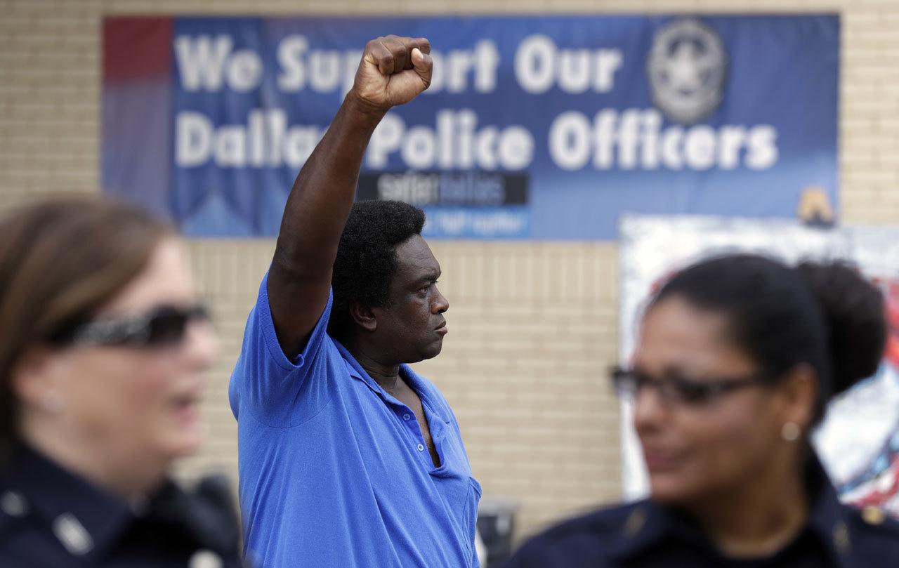 A protester holds up his fist as he stands behind Dallas police officers at their headquarters Monday in Dallas. Five police officers were killed and several injured during a shooting in downtown Dallas last Thursday night. (AP Photo / Eric Gay)