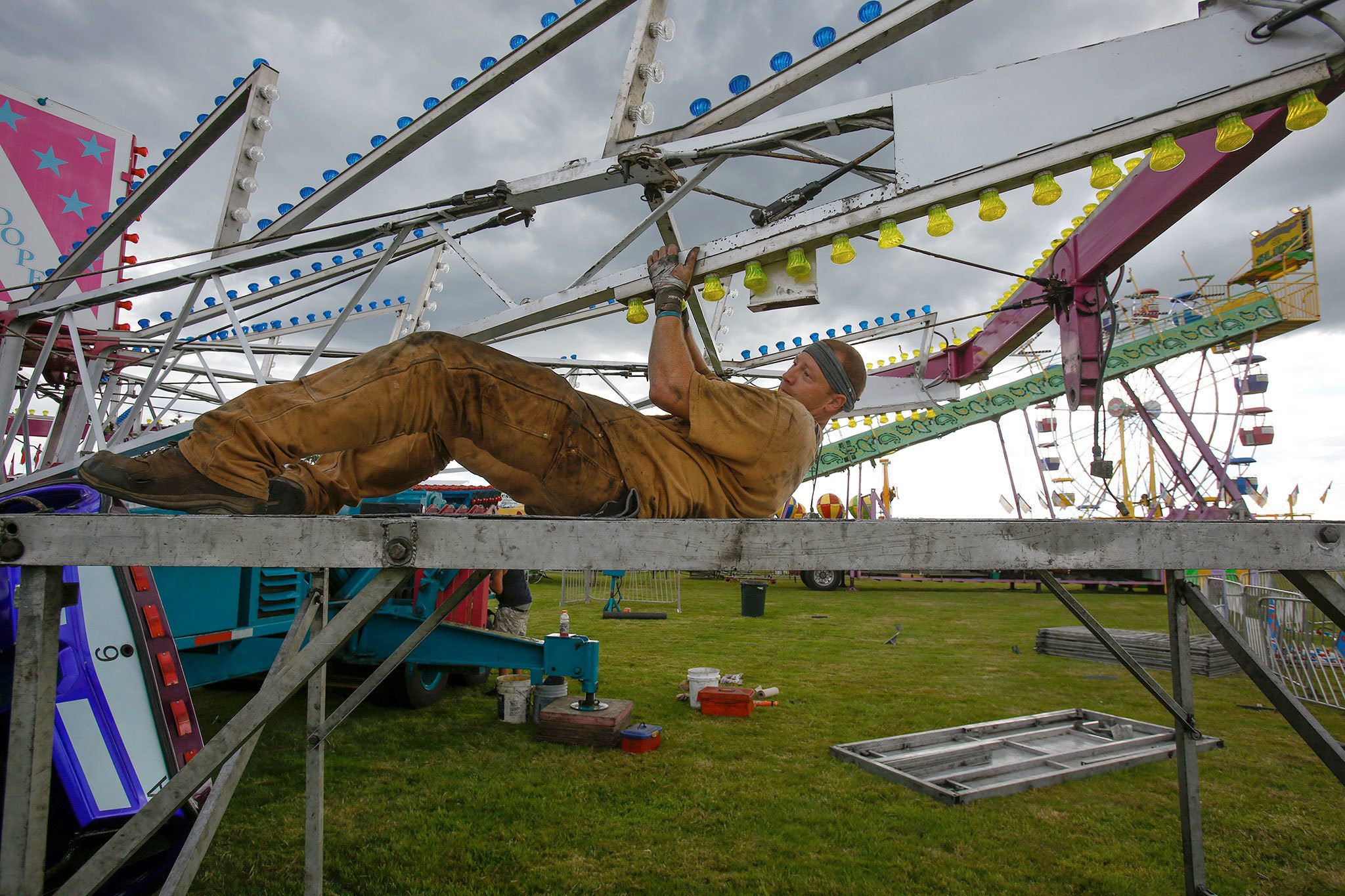 Briefly laying down on the job, Mannie Davis of Davis Shows Northwest, swings the Startrooper ride over his head Tuesday as he builds it to get ready for Kla Ha Ya Days in Snohomish. The city’s big summer festival started July 9 and continues until Sunday. Davis is a third generation family member working the carnival rides. ( Andy Bronson / The Herald )