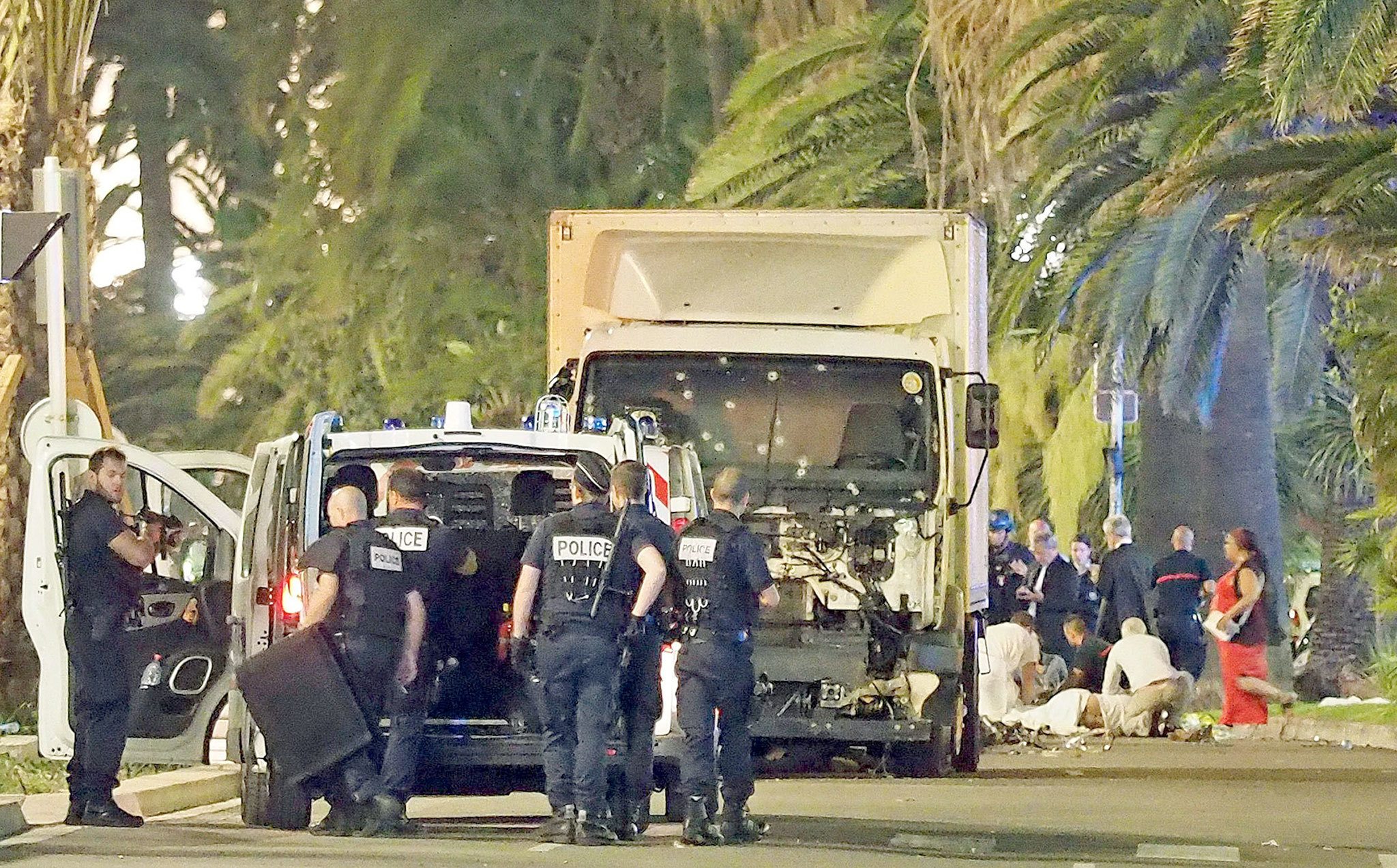 Police stand by as medical personnel attend a person on the ground (right) in the early hours of Friday on the Promenade des Anglais in Nice, southern France, next to the lorry that had been driven into a crowd of revelers late Thursday. (AP Photo)