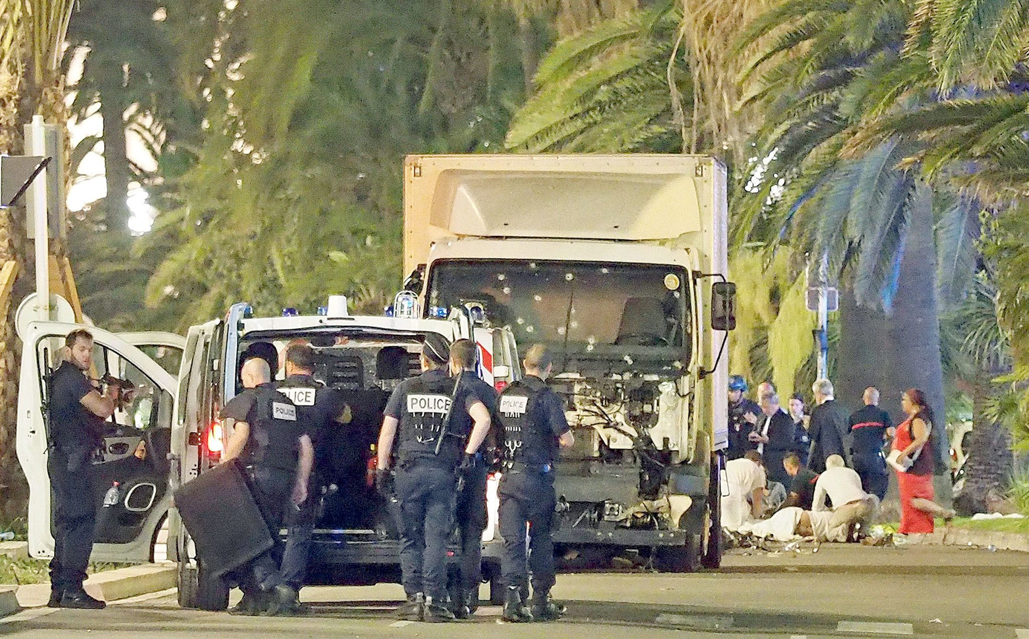 Police stand by as medical personnel attend a person on the ground (right) in the early hours of Friday on the Promenade des Anglais in Nice, southern France, next to the lorry that had been driven into a crowd of revelers late Thursday. (AP Photo)
