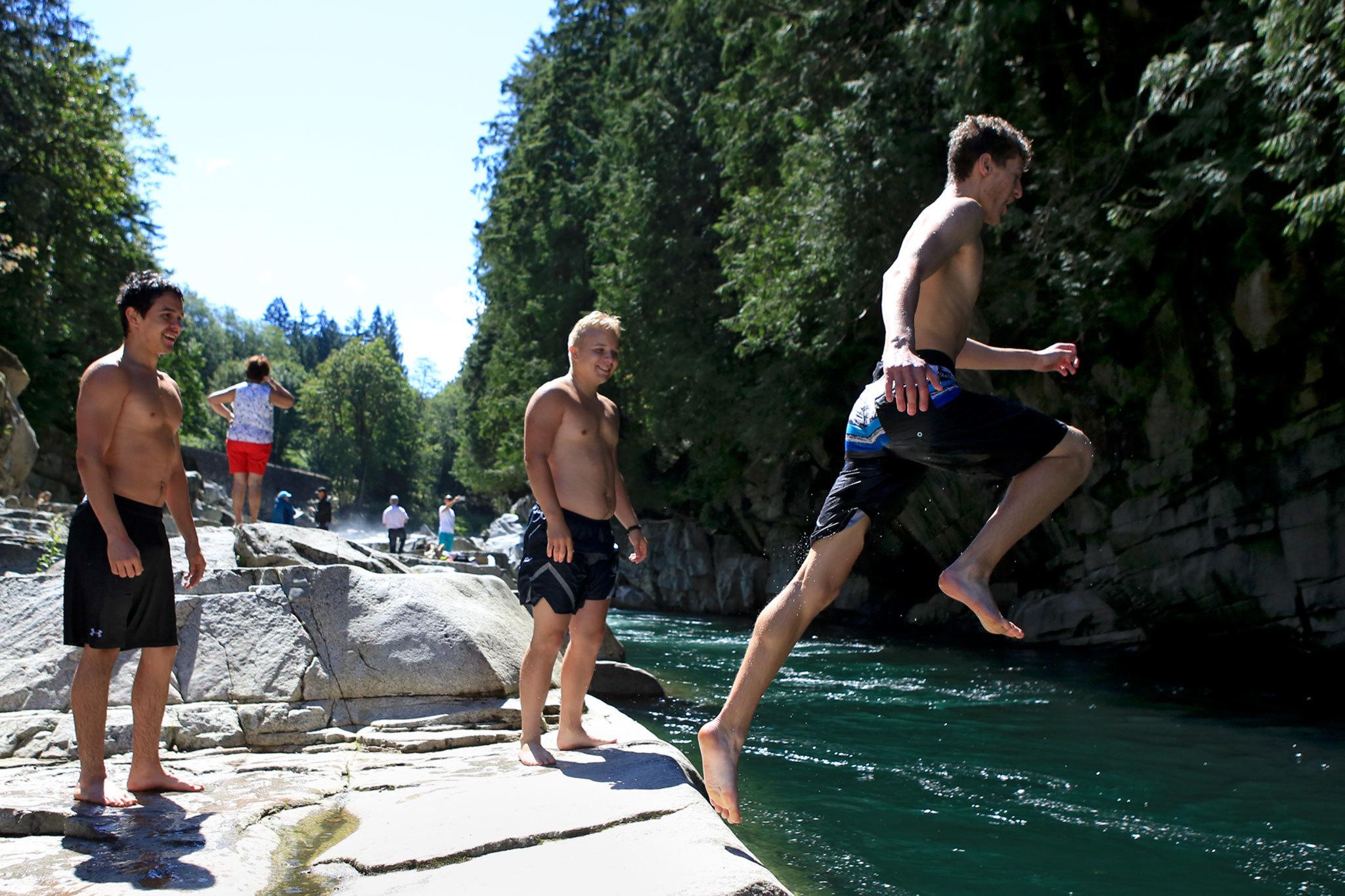Kevin Clark / The Daily Herald                                Johnny Marcello jumps into the swimming hole at Eagle Falls with Ian Vincent, left, and Bostin Otto, center, looking on Thursday morning just outside Index, WA on July 14, 2016.