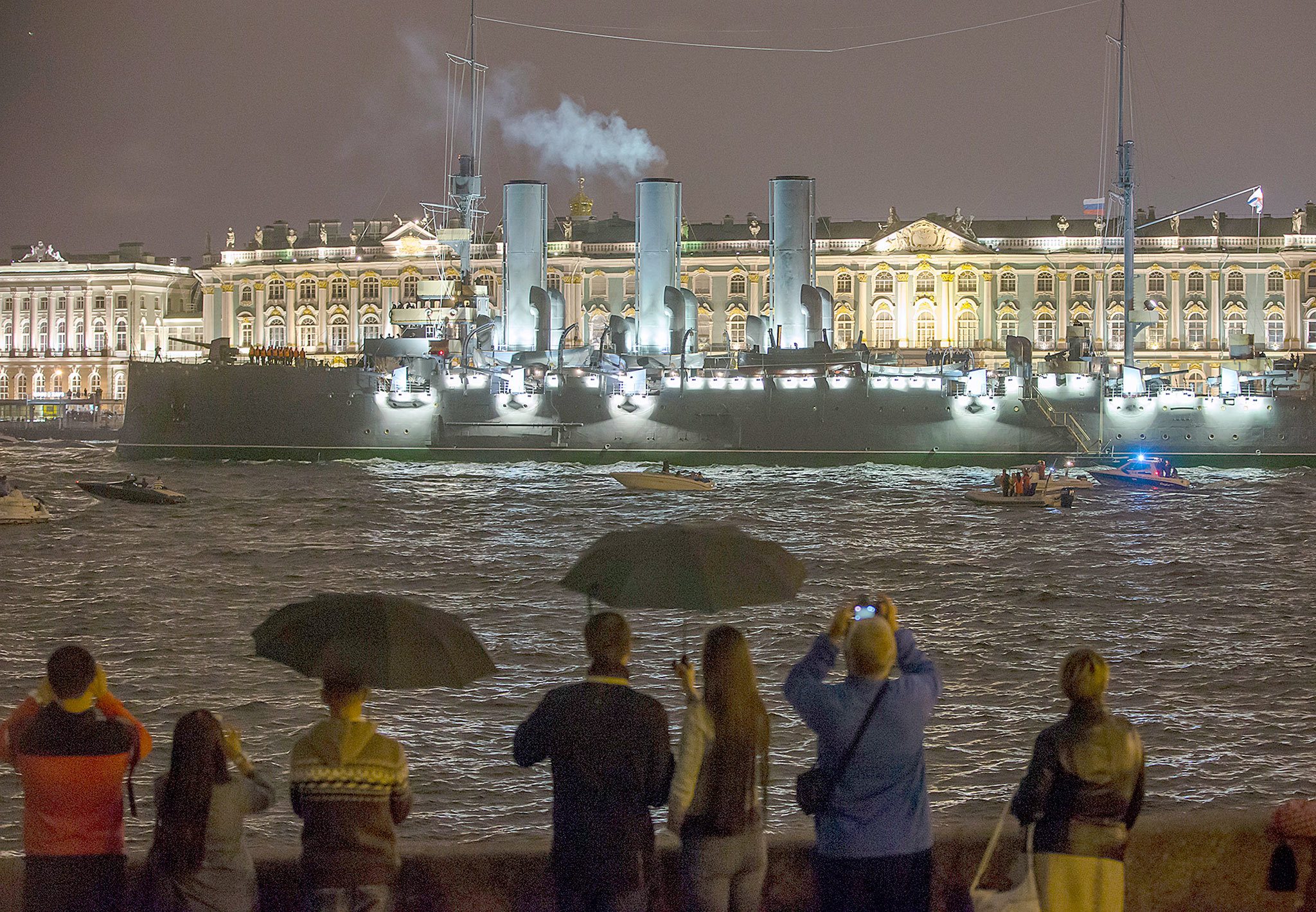 Tug boats tow the Aurora Cruiser past the Winter Palace along the Neva River in St. Petersburg, Russia, early Saturday, July 16, 2016. The cruiser Aurora, which fired the shot that announced the start of the Bolshevik Revolution, was pulled by tugboats up the Neva River early Saturday to return to its mooring in St. Petersburg after nearly two years of repair work. (AP Photo/Dmitri Lovetsky)