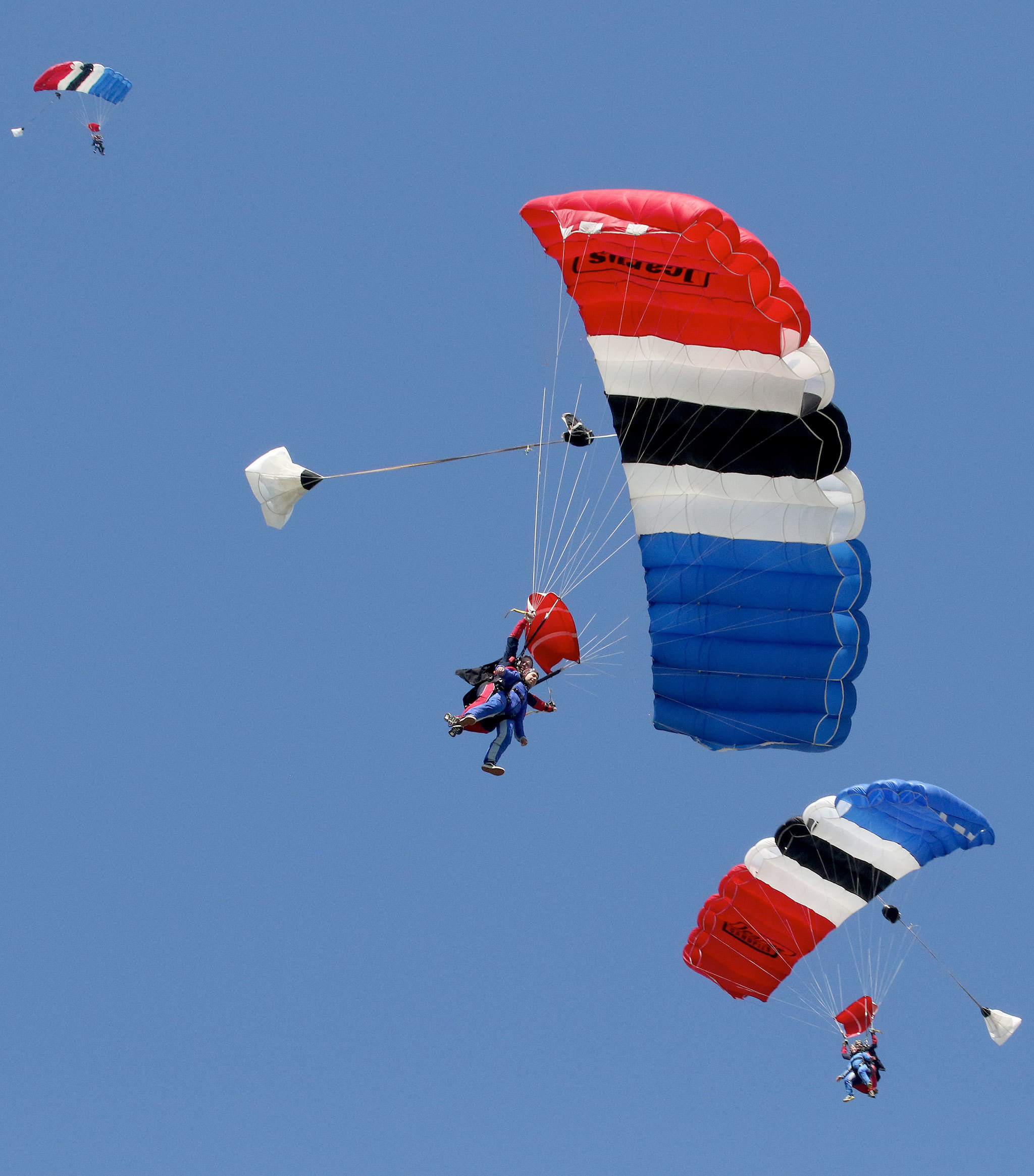 First-time skydivers and their tandem instructors circle in the air under parachutes after free-falling at Skydive Snohomish on Harvey Airfield on April 8 in Snohomish. (Andy Bronson / The Herald)