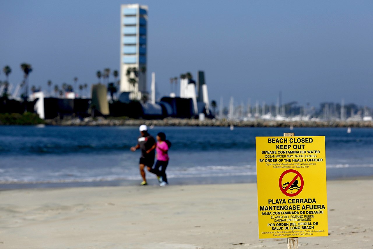A sign is posted on a beach warning of the dangers of sewage contaminated water Tuesday in Long Beach, California. Beaches in Long Beach have been shut down after a sewage spill that began near downtown Los Angeles the day before, flowed down the Los Angeles River to the ocean. (Gary Coronado/Los Angeles Times via AP)