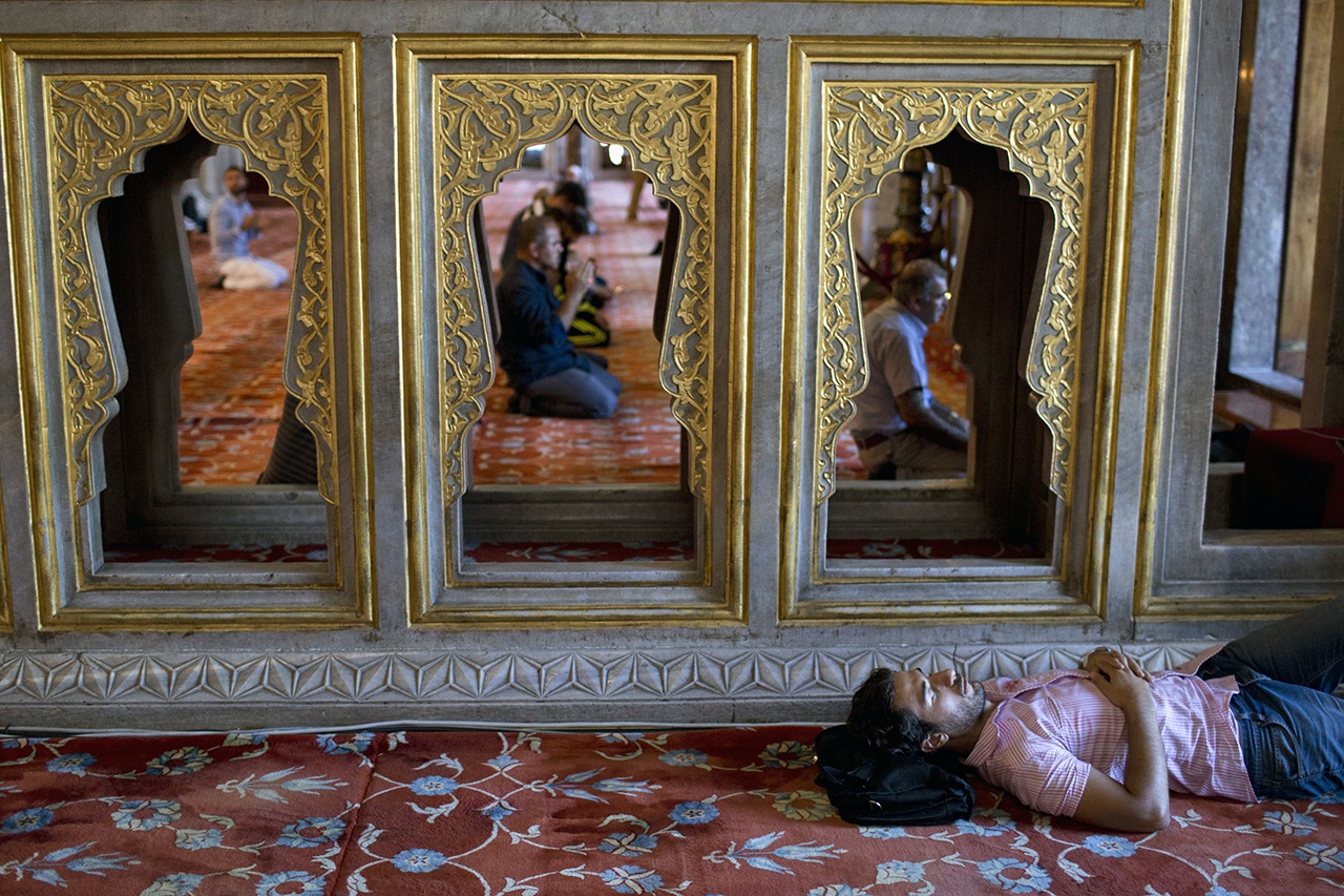 A man rests as people pray inside the Sultan Ahmed Mosque, better known as the Blue Mosque, on July 19 in the historic Sultanahmet district of Istanbul. Days after a failed coup attempt in Turkey, authorities have rounded up close to 9,000 people for alleged involvement in the coup attempt, and banned travel to all academics. (AP Photo/Petros Giannakouris)