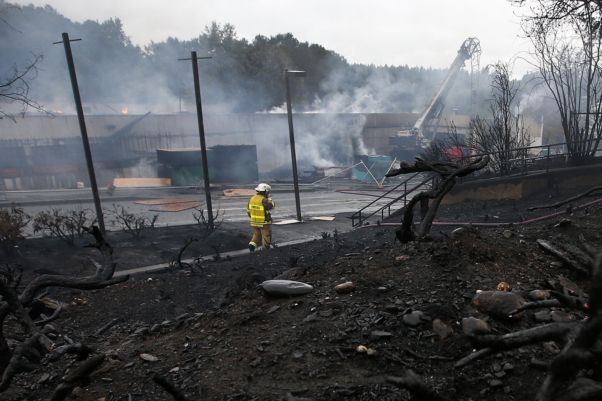A firefighter walks along a scorched area of Main Street in downtown Bothell following a fire that broke out early Friday morning. (Ian Terry / The Herald)