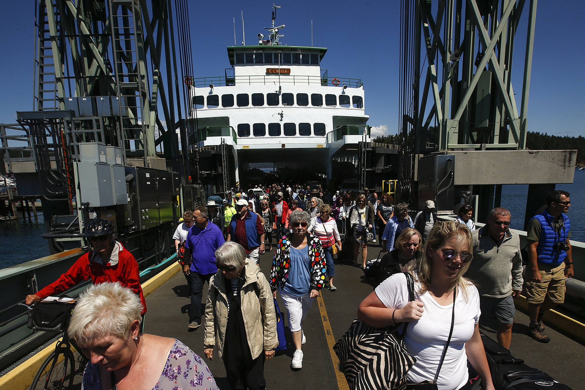 Walk-on passengers stream off a Washington State ferry at the Friday Harbor dock July 14. Reservations are a must for cars during the busy summer months, which makes walking on a good option for last-minute day trips to the San Juan Islands. (Ian Terry / The Herald)