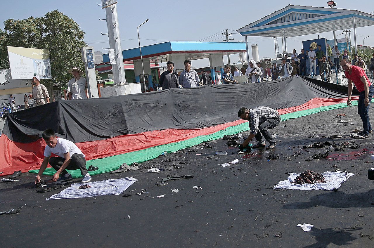 Afghans gather property left behind by victims of a deadly explosion that struck a protest march by ethnic Hazaras in Kabul on Saturday. (AP Photo/Massoud Hossaini)