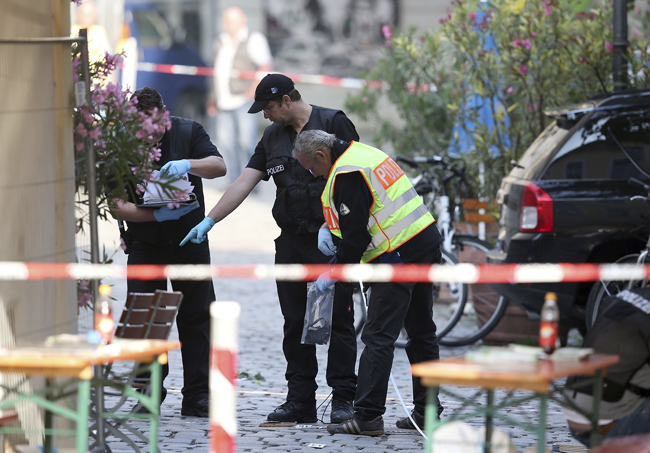 German police investigates at the site in Ansbach, Germany, on Monday, where a failed asylum-seeker from Syria blew himself up and wounded 15 people after being turned away from an open-air music festival in southern Germany. The man recorded a cell phone video of himself pledging allegiance to the Islamic State group before he tried to get into the outdoor concert with a bomb-laden backpack. (Daniel Karmann/dpa via AP)
