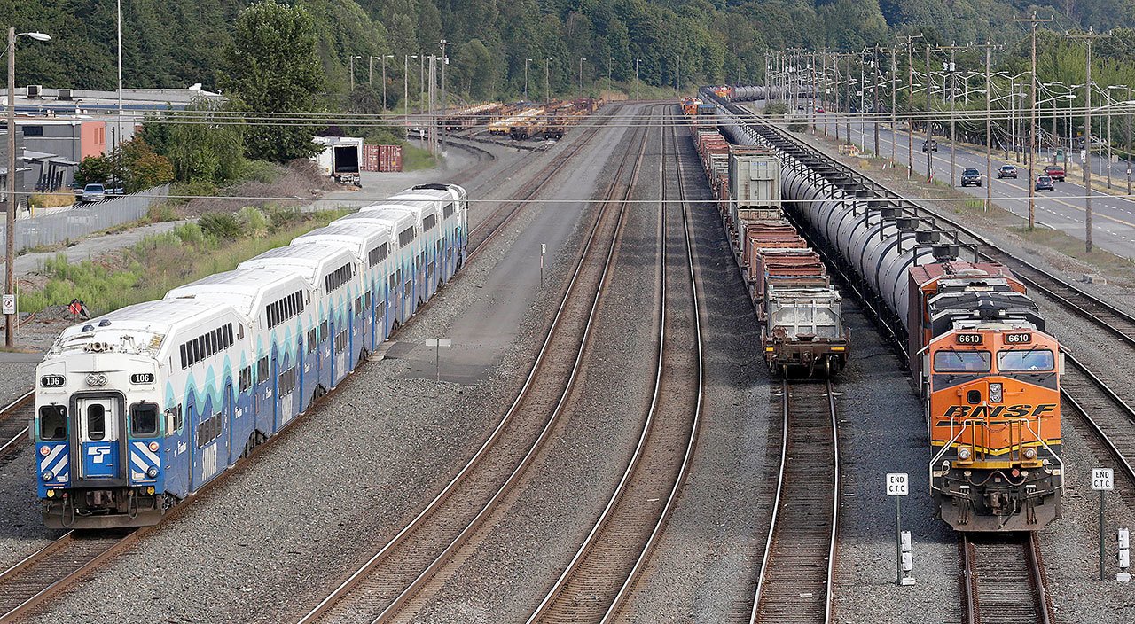 A passenger commuter train passes one of two mile-long oil trains parked adjacent to the King County Airport in Seattle on July 27. As oil trains began rolling through its downtown a few years ago, Spokane was among the first cities to pass a resolution calling for tougher state and federal safety regulations. But when an oil train derailed in a fiery crash in Oregon last month, after earlier rumbling through the Eastern Washington city, some city leaders didn’t want to wait for the federal government to act. The Spokane City Council decided 6-0 to ask voters whether the city should fine companies that ship crude oil or coal by rail through downtown, Wednesday. (AP Photo/Elaine Thompson, File)