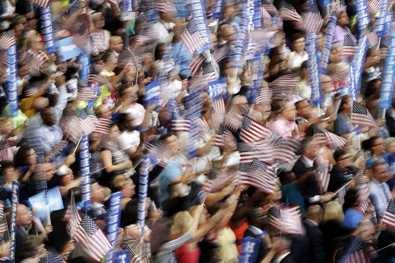 In this photo taken with a slow shutter speed, people wave flags and signs as Democratic presidential nominee Hillary Clinton speaks during the final day of the Democratic National Convention on Thursday in Philadelphia. (AP Photo/John Locher)