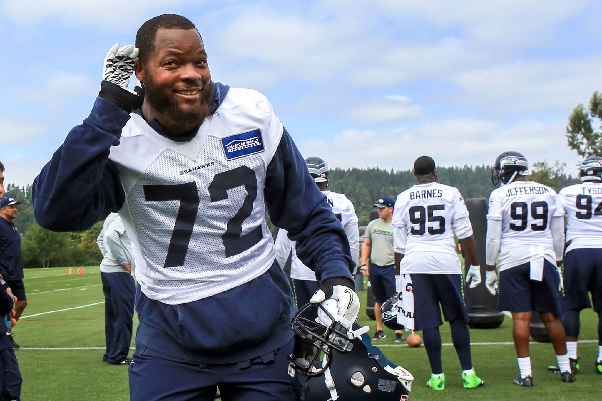 The Seahawks’ Michael Bennett listens for fan support during the first day of training camp Saturday at the Virginia Mason Athletic Center in Renton. (Kevin Clark / The Herald)