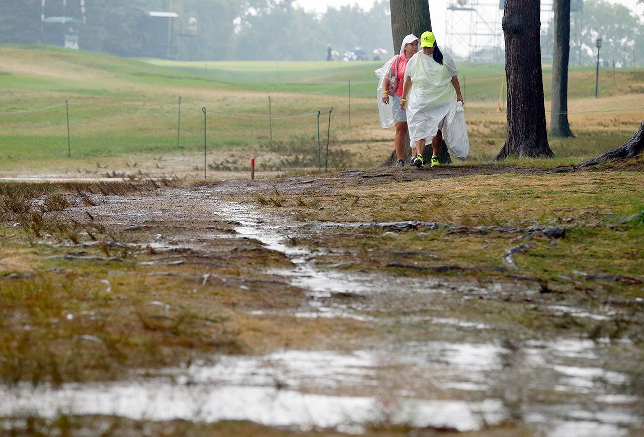 Women walk by the 18th hole after third round play was suspended for the day at the PGA Championship at Baltusrol Golf Club in Springfield, N.J. on Saturday. (AP Photo/Tony Gutierrez)