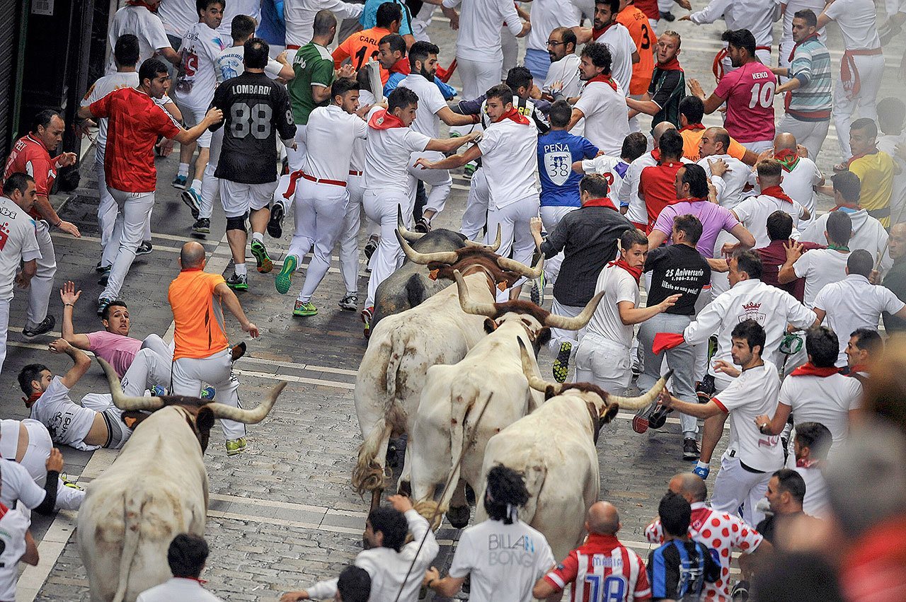 Revelers run with fighting bulls during the third running of the bulls at the San Fermin Festival, in Pamplona, Spain, on Saturday. (AP Photo/Alvaro Barrientos)
