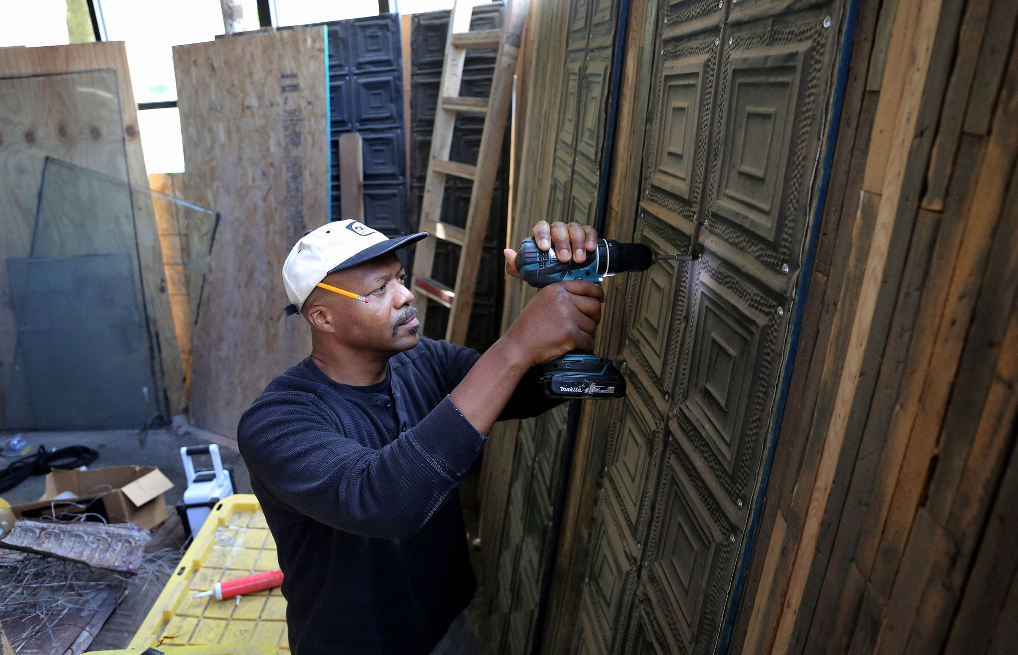 Tsadakeeyah Emmanuel works on tiles to be used on the ceiling of his new vegan catering space in Chicago. Emmanuel said he once used an online lender for a loan, but was charged 75 percent interest.