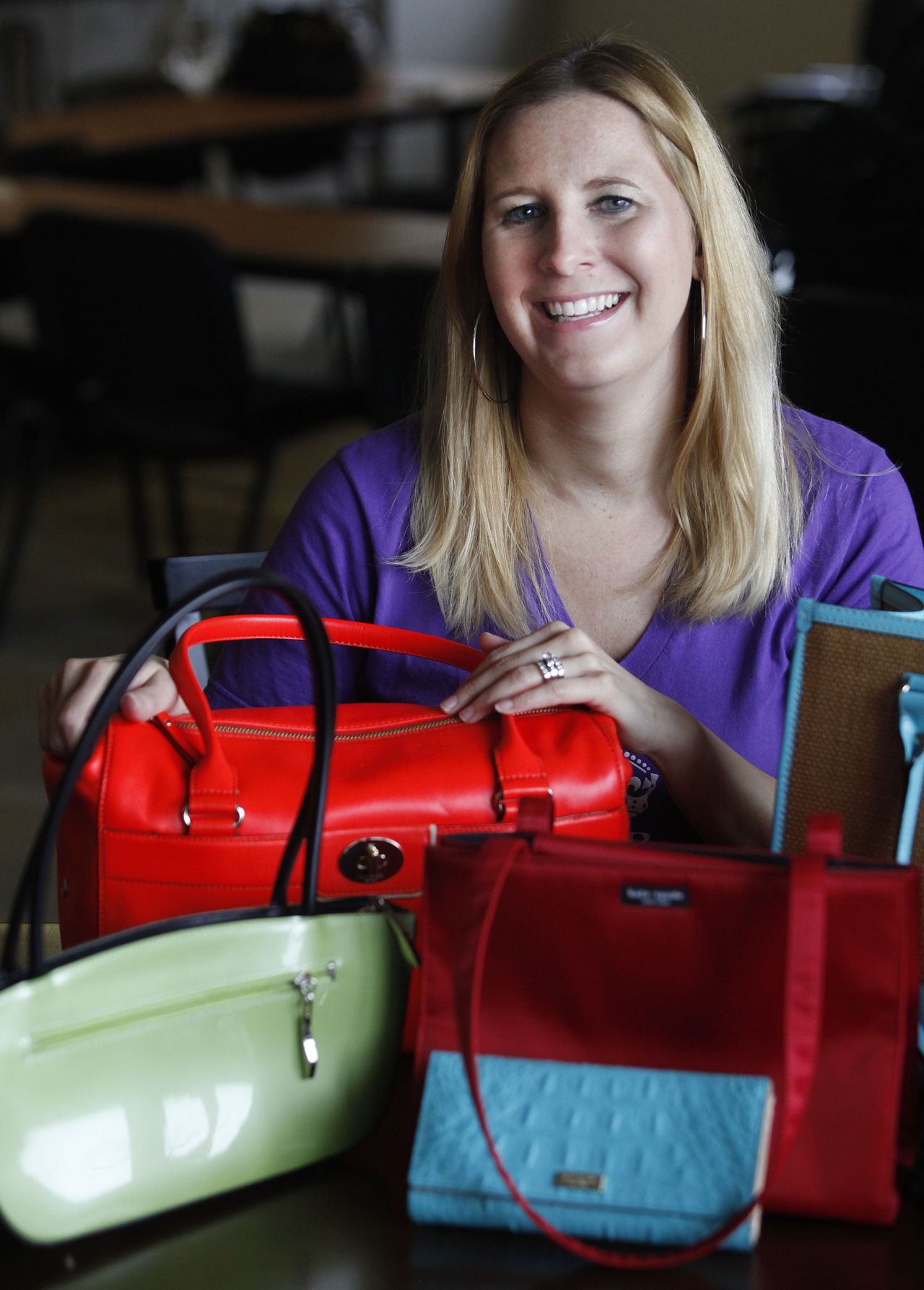 Stephanie Civey, events and marketing coordinator for Domestic Violence Services, poses with purses up for auction at a prior Domestic Violence luncheon fundraiser.