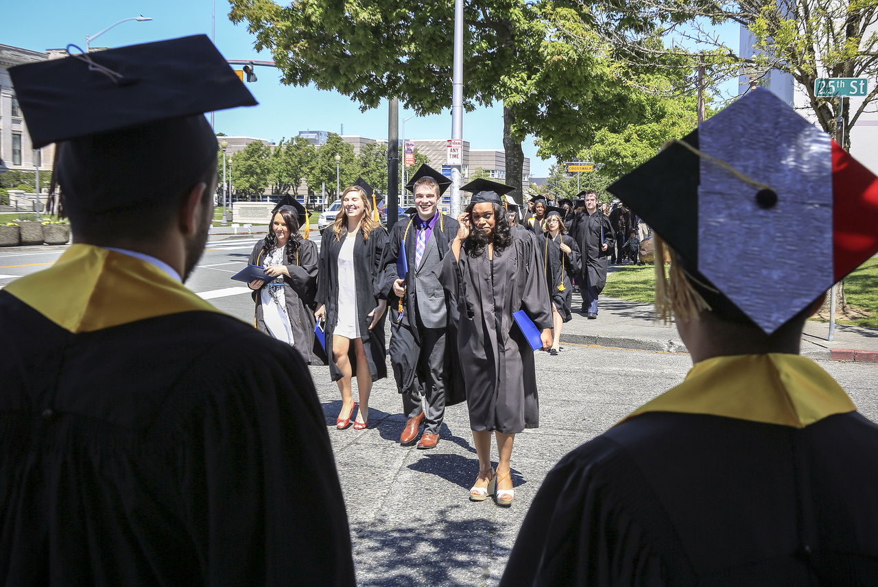 Ali Shams (left) and Misael Salmon watch and wait for fellow graduates after Trinity Lutheran College’s final commencement ceremony Saturday.