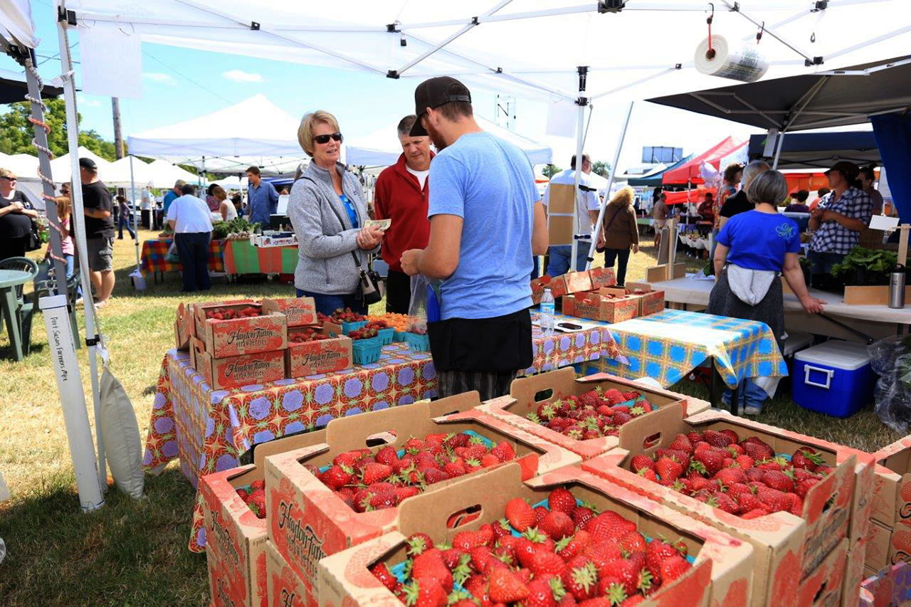 Patrons buy fresh strawberries at the Port Susan Farmers Market in Stanwood. With the help of a $99,990 federal grant, the market is moving to a larger area.
