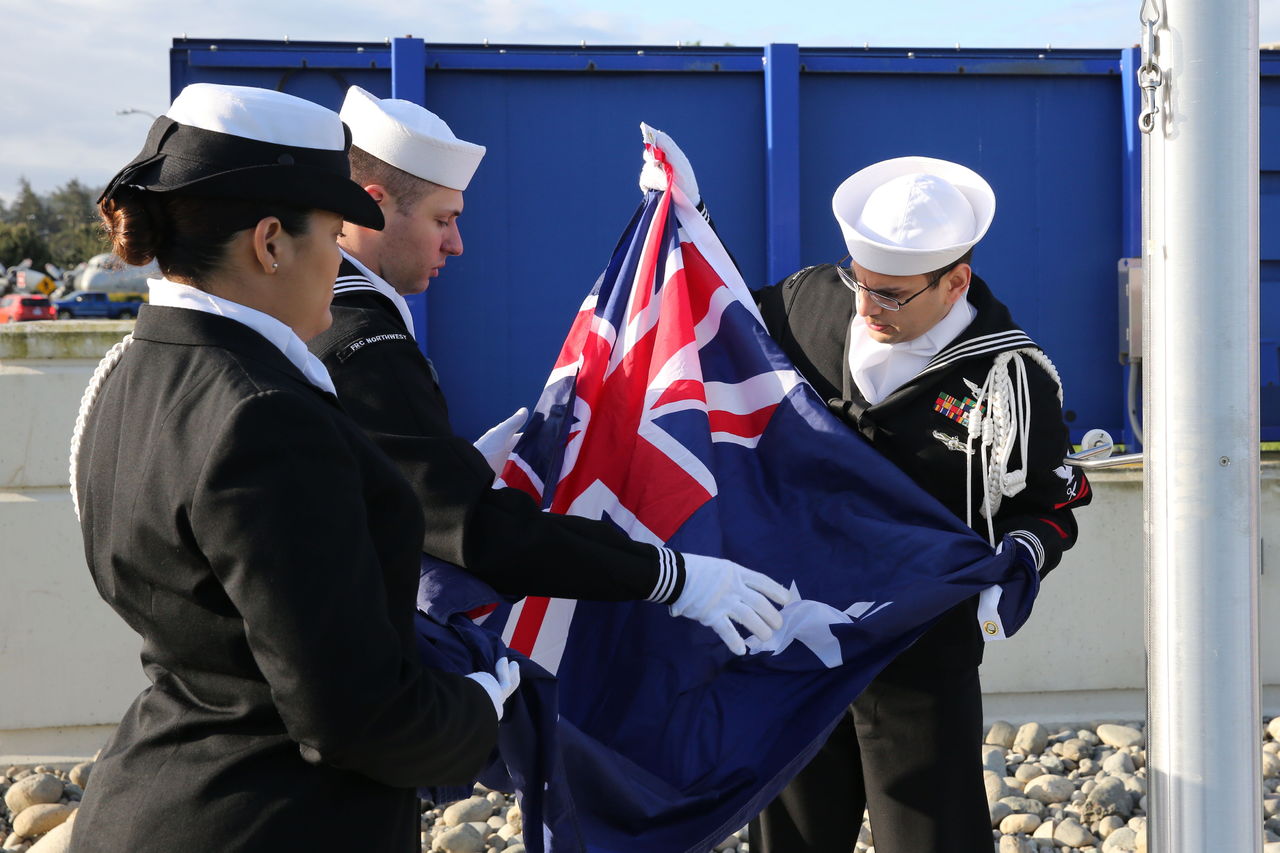 Aviation Structural Mechanic 2nd Class Michael Barrera from Fleet Readiness Center Northwest (center) assists Airman Martha Risoldi and Intelligence Specialist 1st Class Janpier Mendez on April 25 at Naval Air Station Whidbey Island as they prepare to raise the Australian national ensign during a flagpole ceremony. The Oak Harbor base hosted the ceremony in honor of the joint cooperation between the U.S. Navy, Royal Australian Air Force and Royal Canadian Navy.