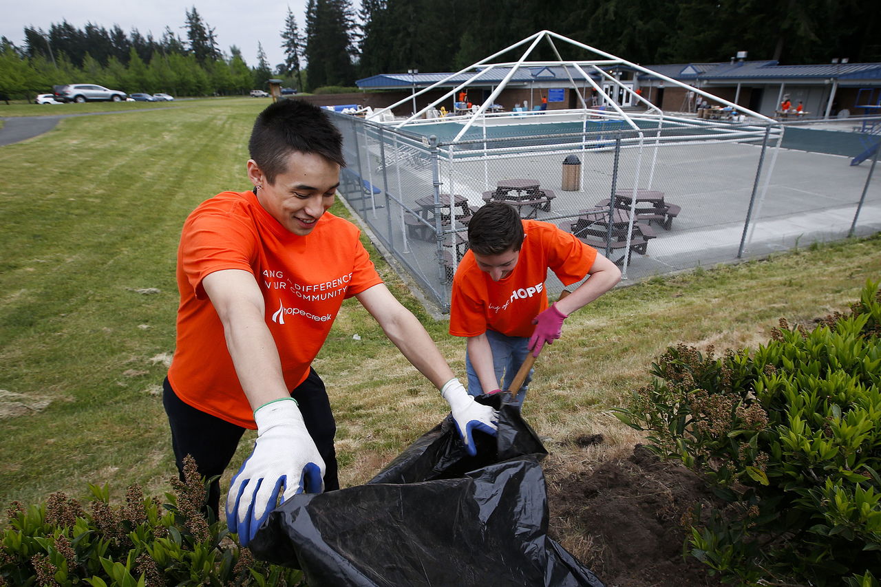 Glacier Peak High School students Tristan Anderson (left) and Lance Le Meur rake up weeds and clean flowerbeds near McCollum Park Pool in Mill Creek.