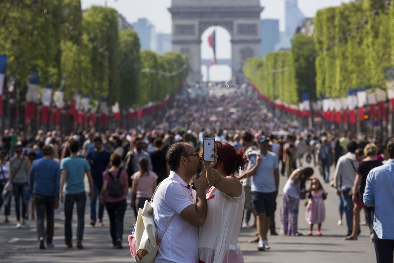 A couple kisses as they take a selfie on the Champs Elysees in Paris, France, on Sunday. Pedestrians have taken over the Champs Elysees as part of a new program to ban traffic from the famous Paris avenue once a month. The initiative, for what is usually one of the busiest roads in the French capital, was launched by Paris Mayor Anne Hidalgo and is aimed at reducing pollution in the city.