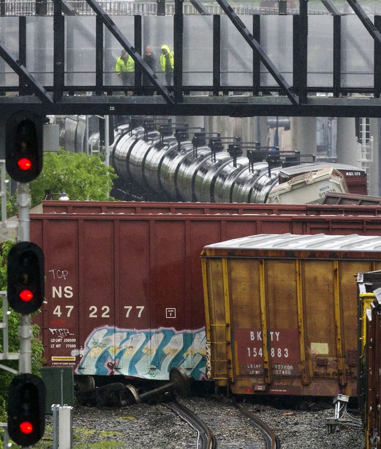 Officials look down from a Metro pedestrian bridge at several overturned train cars after a CSX freight train derailed Sunday near a Metro stop in Washington, D.C.