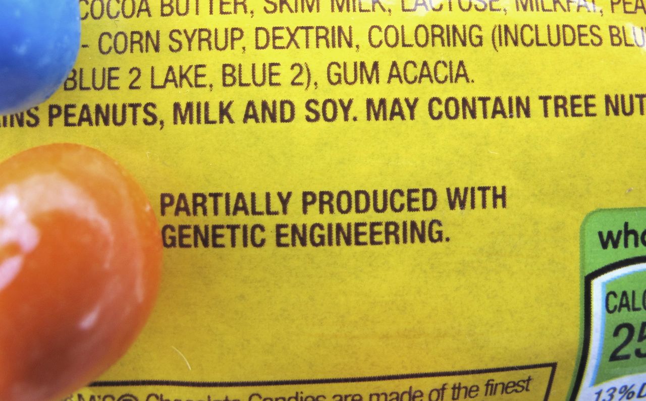 A new disclosure statement is displayed on a package of Peanut M&M’s candy in Montpelier, Vermont, saying they are “Partially produced with genetic engineering.” Genetically manipulated food remains generally safe for humans and the environment, a high-powered science advisory board declared in a report Tuesday.