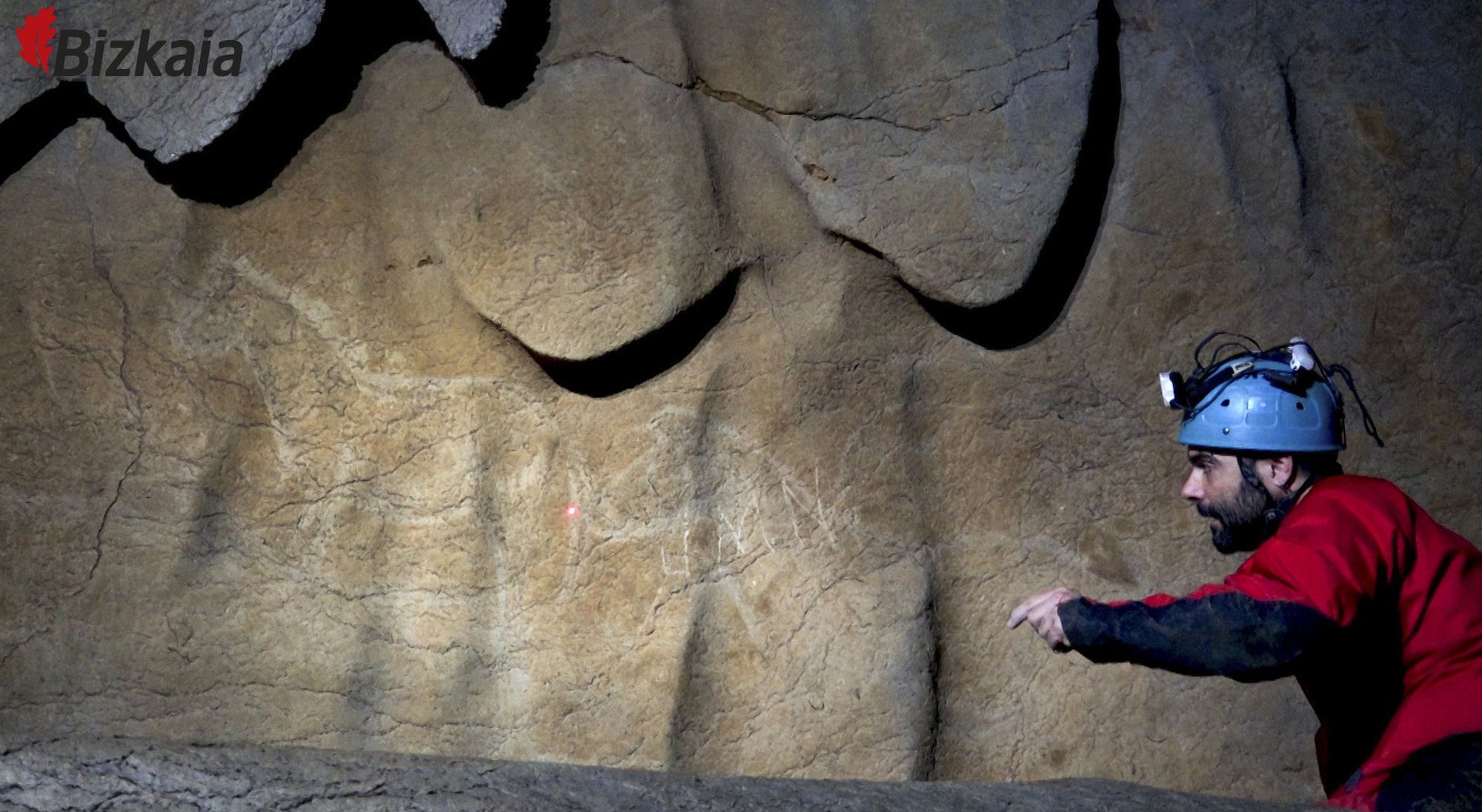 An archaeologist points to a another drawing in the cave.