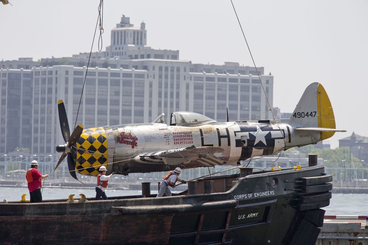 Officials place a World War II vintage P-47 on the Wall Street Heliport pier Saturday after removing it from the Hudson River. The Thunderbolt aircraft crashed into the river Friday.