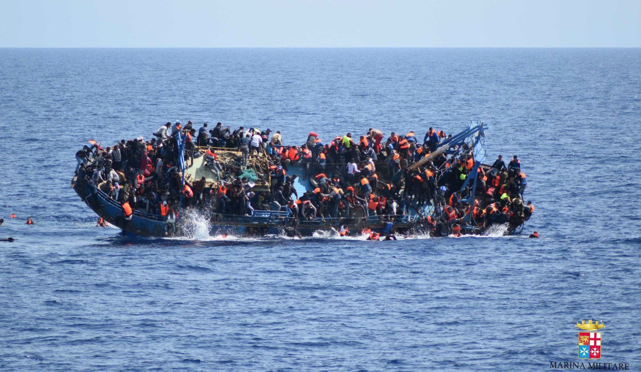 People jump out of a boat right before it overturns off the Libyan coast Wednesday.