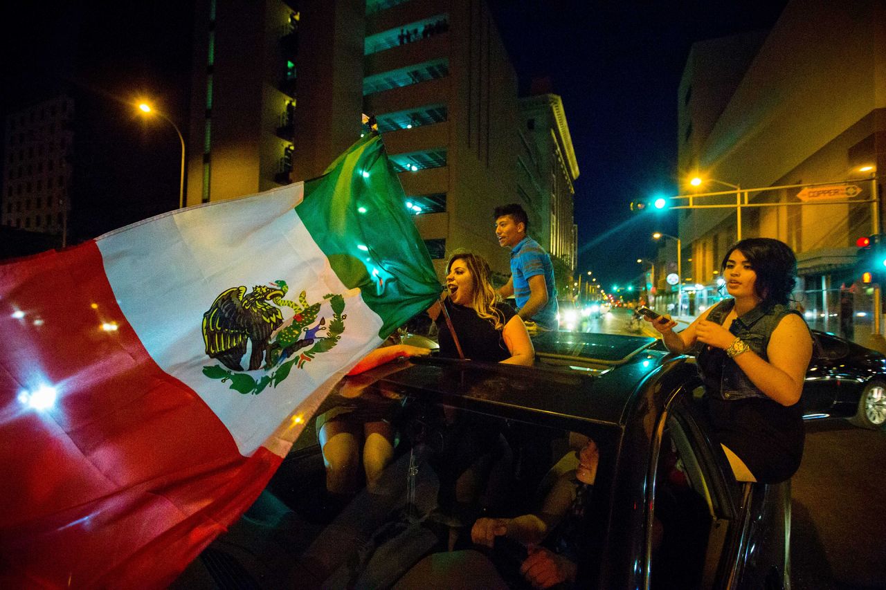 A woman waves the Mexican flag while driving past the Albuquerque Convention Center after a rally by Republican presidential candidate Donald Trump Tuesday in Albuquerque, New Mexico.