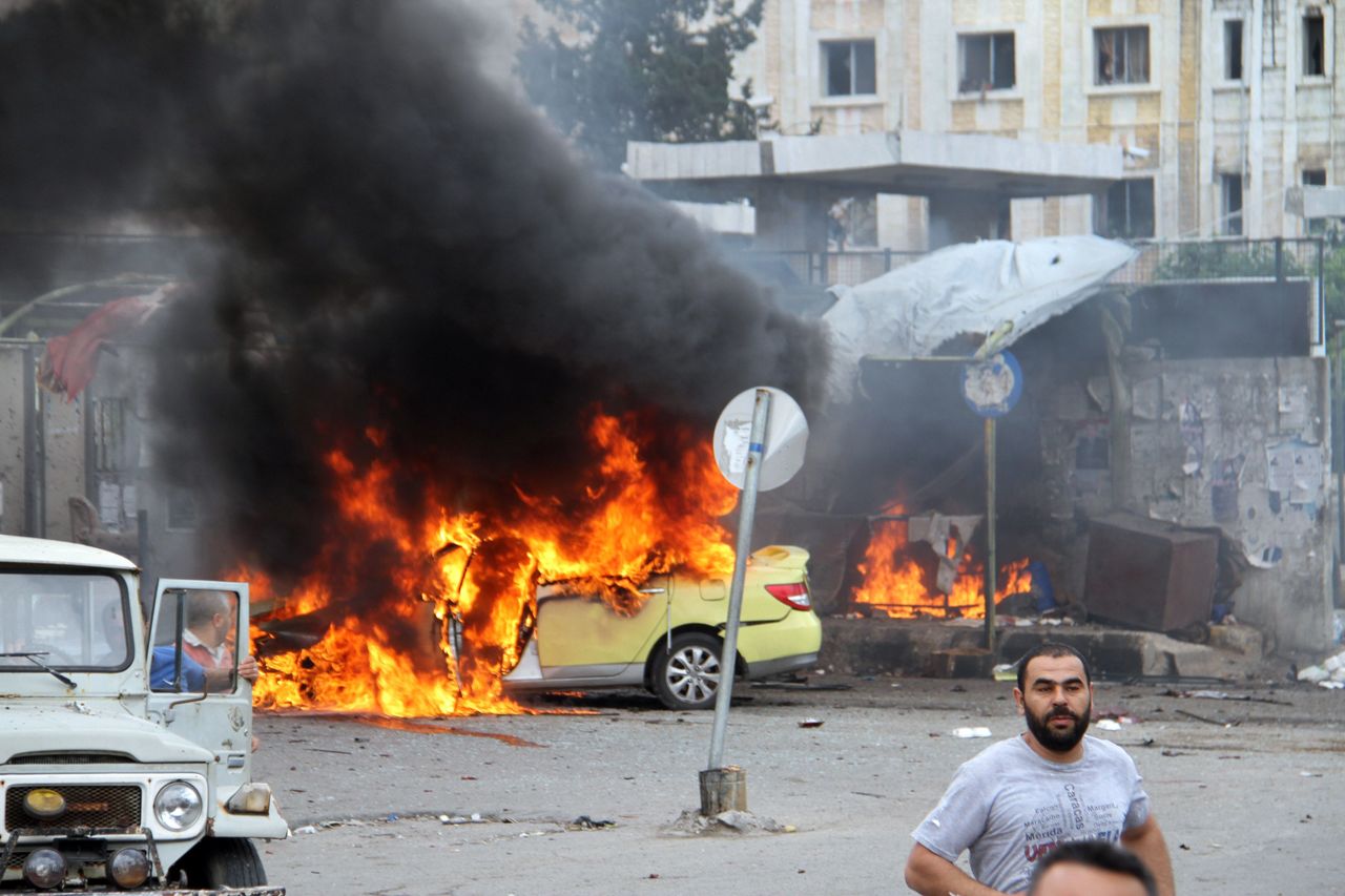 Syrians gather in front of a burning car at the scene where suicide bombers blew themselves up in Tartus, Syria, on Monday. The Islamic State group claimed responsibility for the attacks.